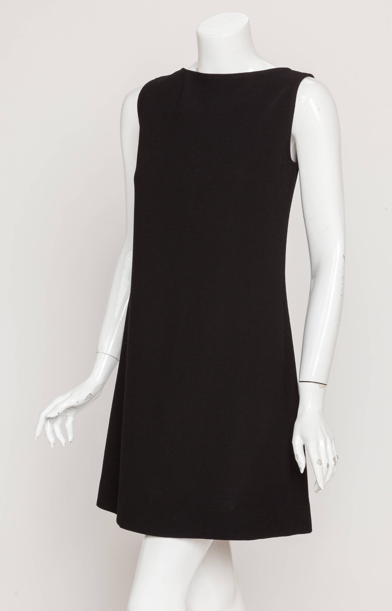 A vintage Pierre Cardin black wool crepe shift dress with three cutouts at the back. The dress fastens at the back with a hook and eye behind a small satin bow at the neck. No fabric tag but size tag is 38. In excellent condition. Labeled: Pierre