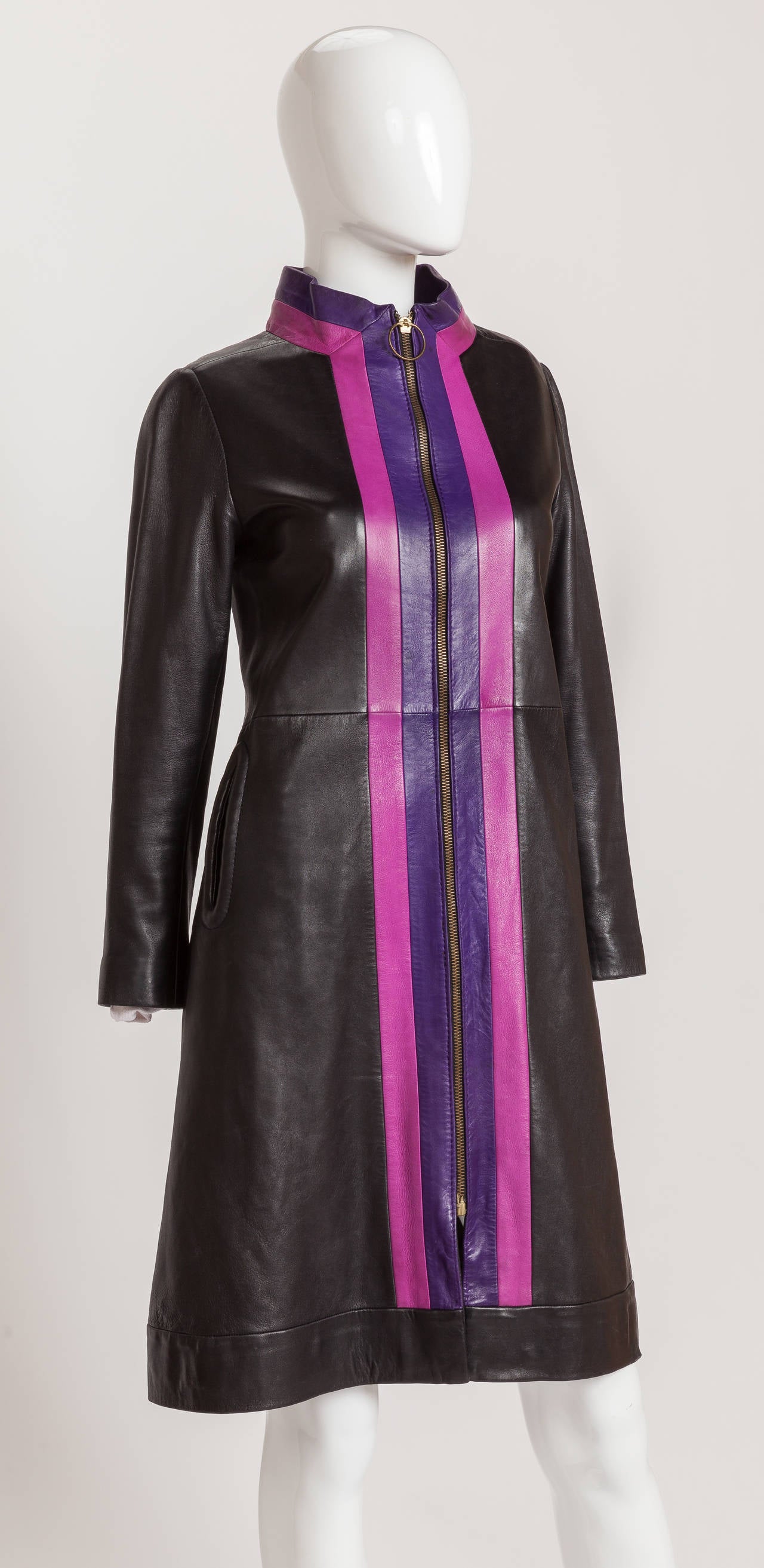 Simply put - this is a killer coat and one of my all-time favorite Pierre Cardin garments. This 1970s body hugging knee-length coat is made from supple, soft black leather and is trimmed with purple and fuchsia pink leather stripes down the center