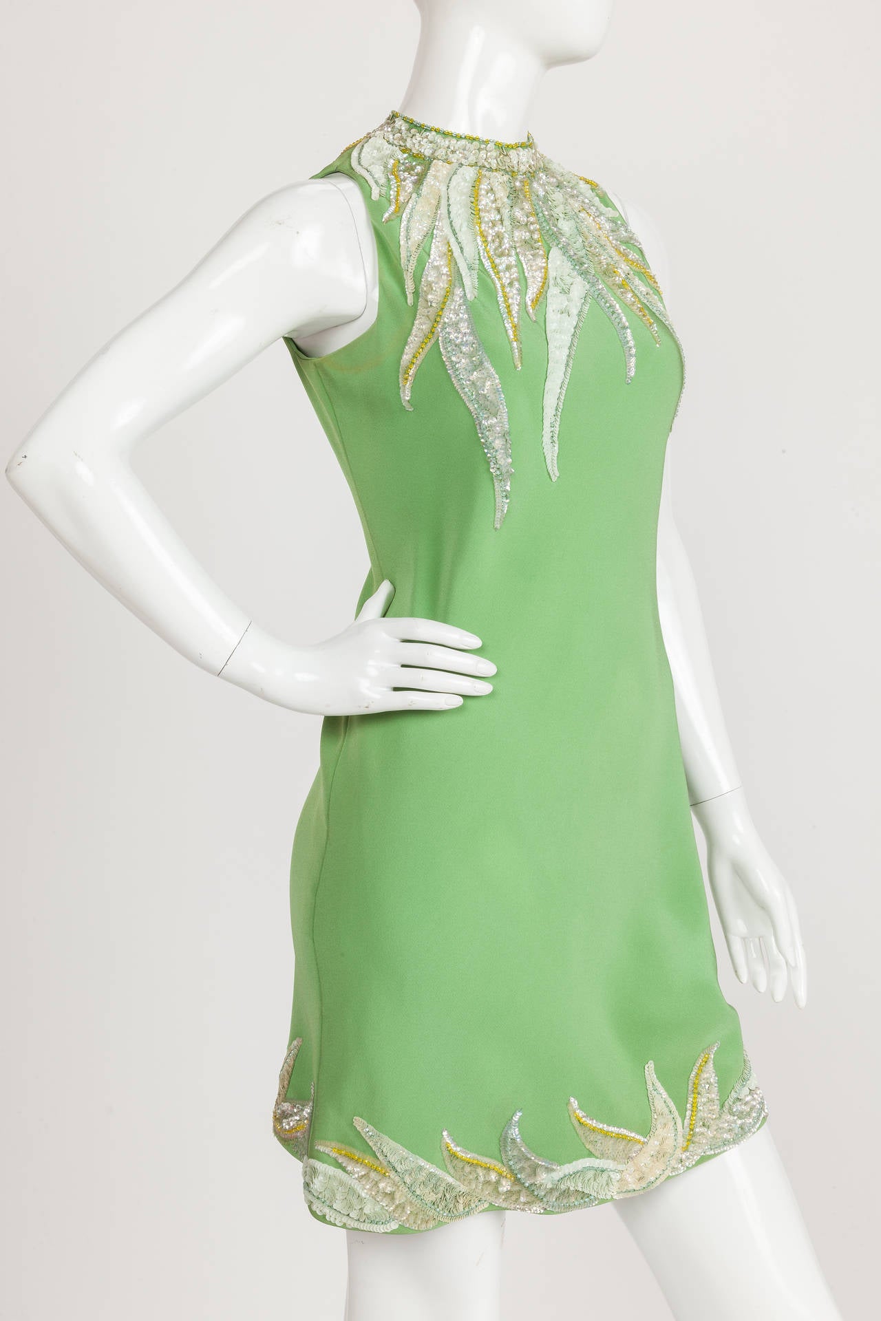 A circa 1967 Pierre Cardin haute couture green sequined silk crêpe cocktail dress that features a keyhole opening at the back. The main draw of this slinky silk cocktail dress are the shades of yellow, green and light violet appliquéd and