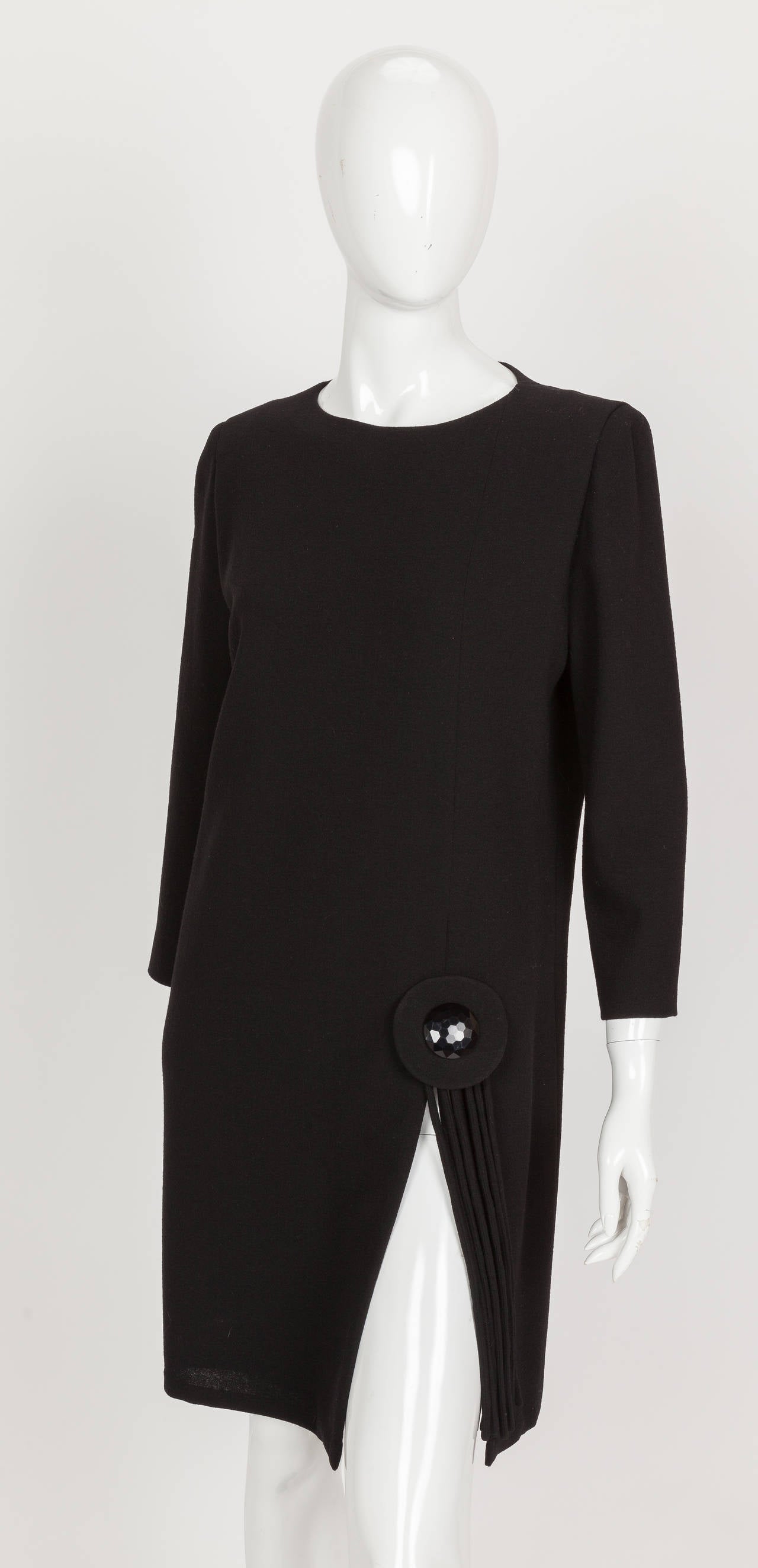A circa 1992 Pierre Cardin haute couture black wool crepe cocktail dress with a thigh-high slit featuring tassel trim and an oversized, faceted button. Zipper closure up the back, lined in black silk. In excellent condition. No size tag but my guess