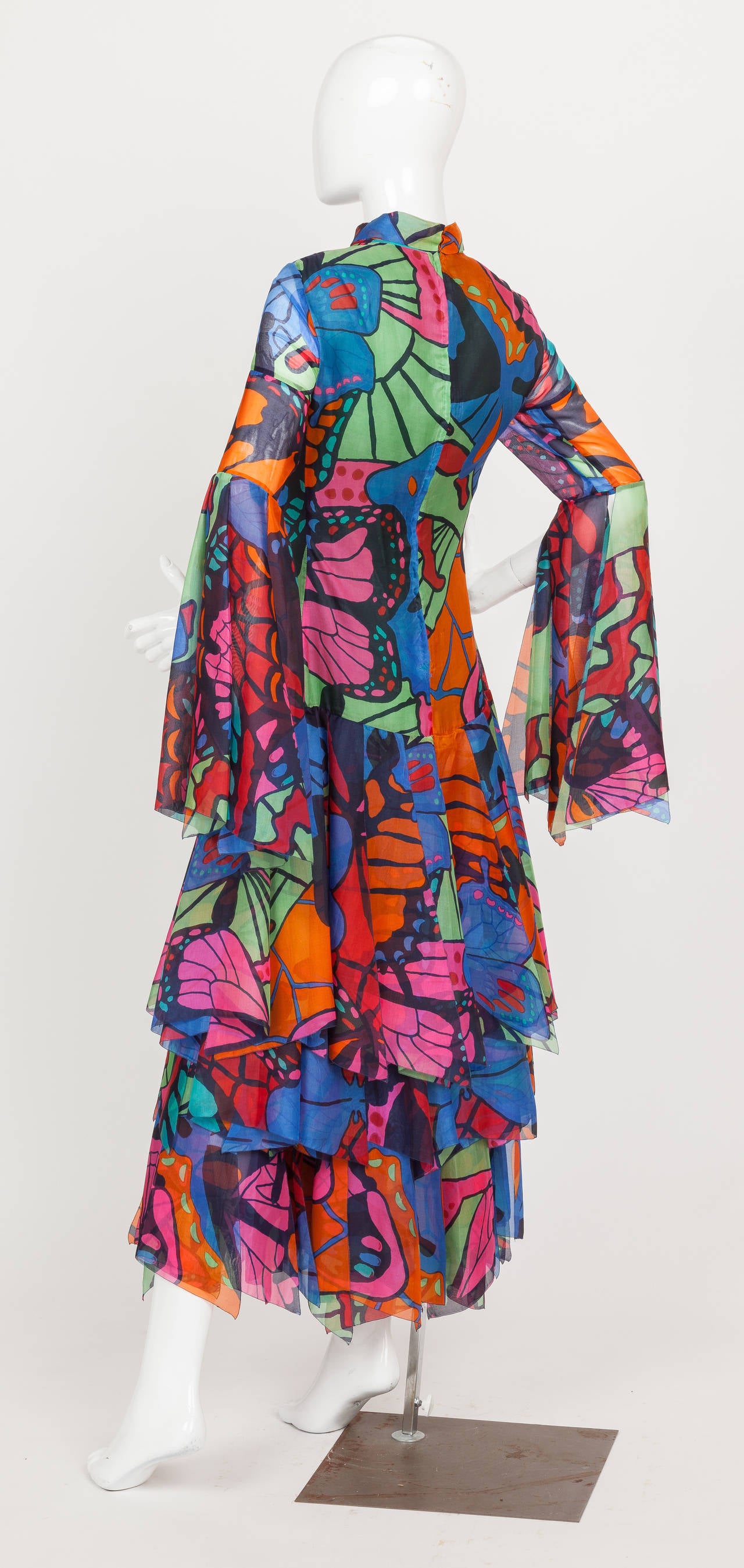 A circa 1970-1971 Pierre Cardin ankle-length gown of fine cotton voile with large abstract butterfly motif. Features long sleeves made of flowing panels, a high band collar, a three-tiered skirt covered with multiple layers of floating panels, and