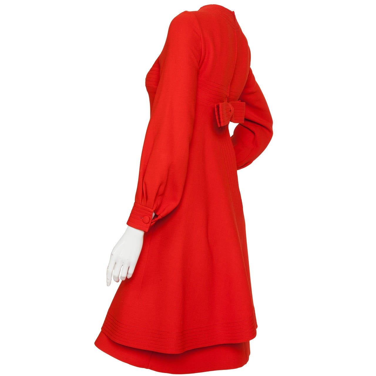 A circa 1970 Pierre Cardin long-sleeved tomato red wool dress with channel stitched design motif. The A-line overdress features an eight-inch center front slit just above the hem, decorative frontal faux slat pockets and channel stitching at the