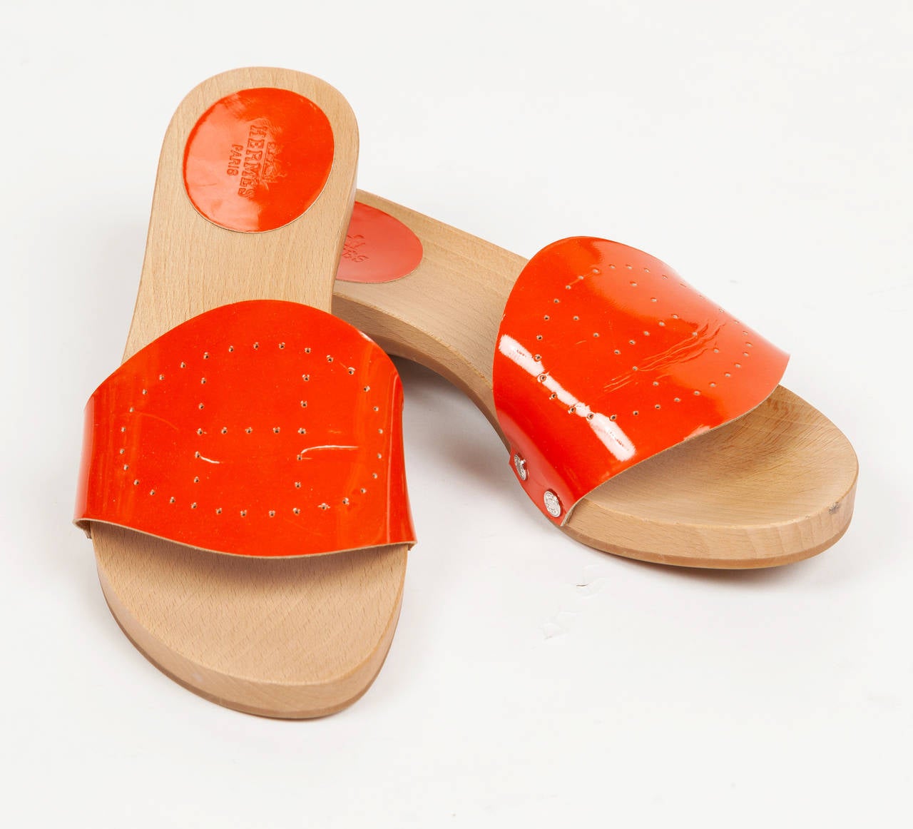 A pair of Hermes wooden sandals or slides with orange patent leather perforated 