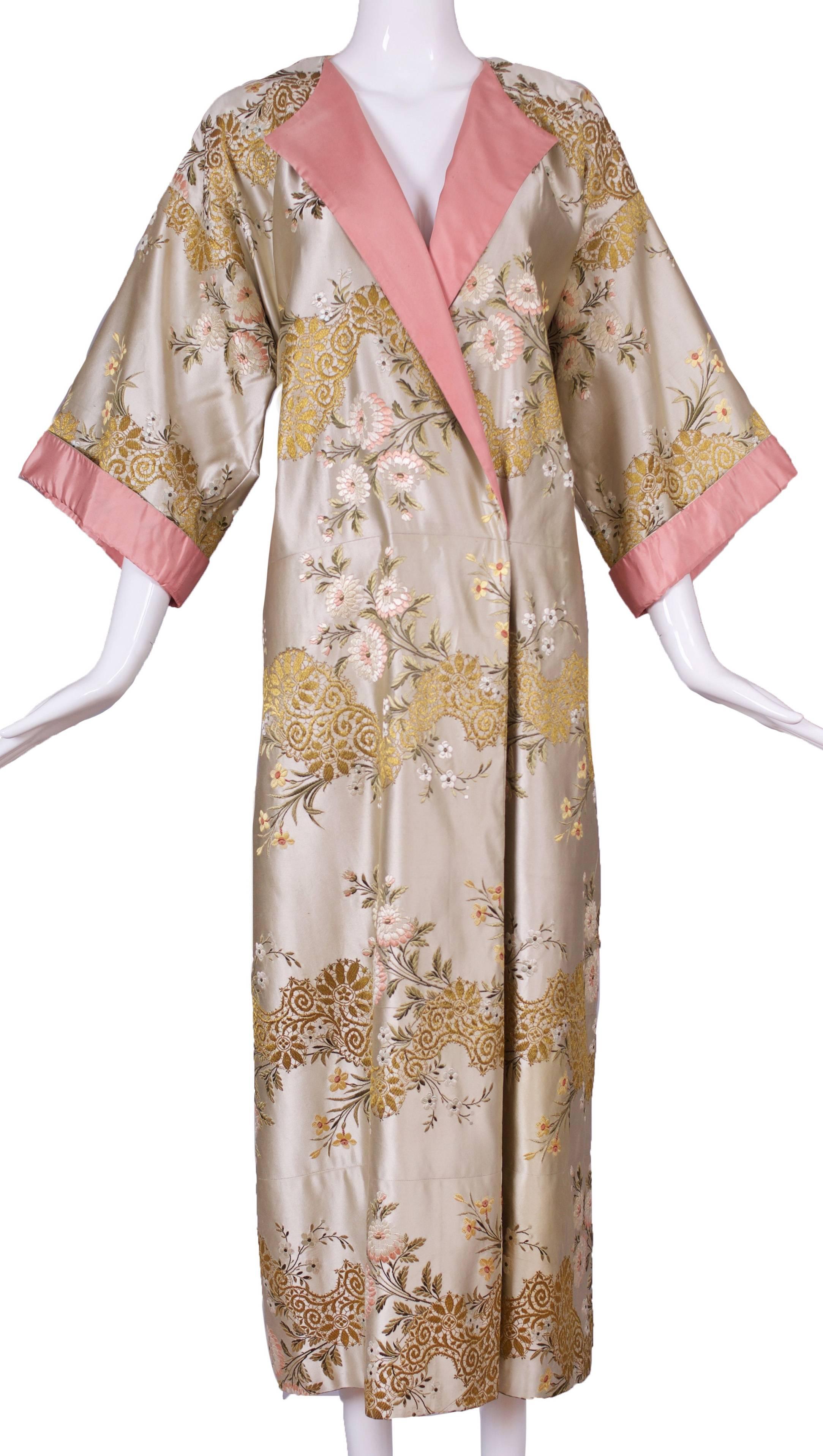 A circa 1960 Madame Gres haute couture kimono evening dress in pastel hues and a floral embroidered motif that includes gold thread. Trimmed at the neck, 3/4 sleeves and an attached waist tie with rose pink silk taffeta. The kimono can be worn with
