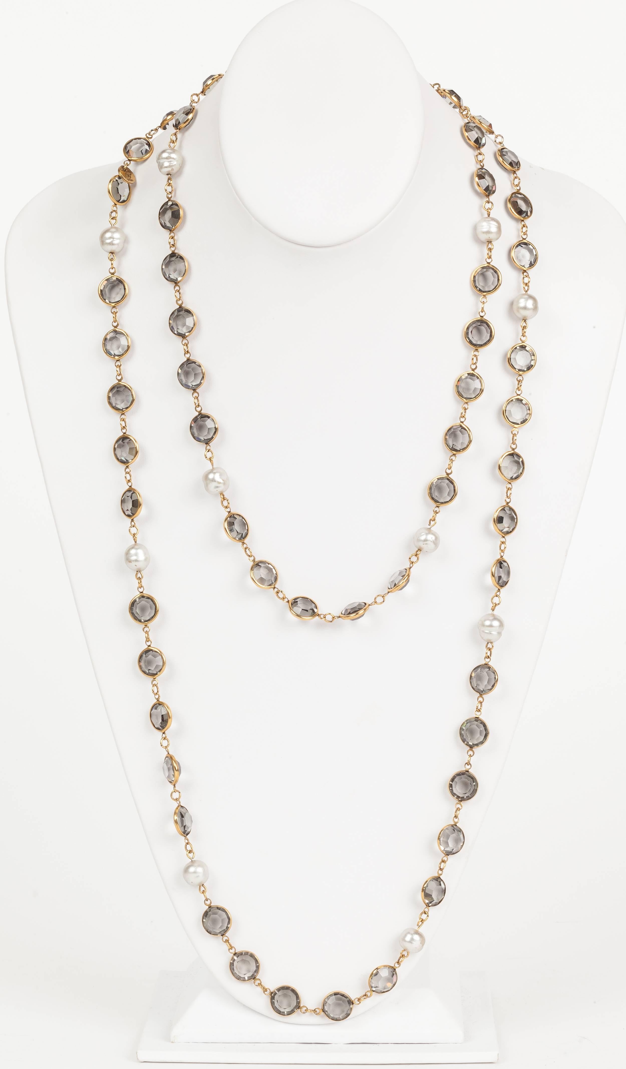 A 1981 Chanel sautoir necklace comprised of faux pearls and bezel-set smoky crystals in gold tone surrounds. In excellent condition. Stamped 
