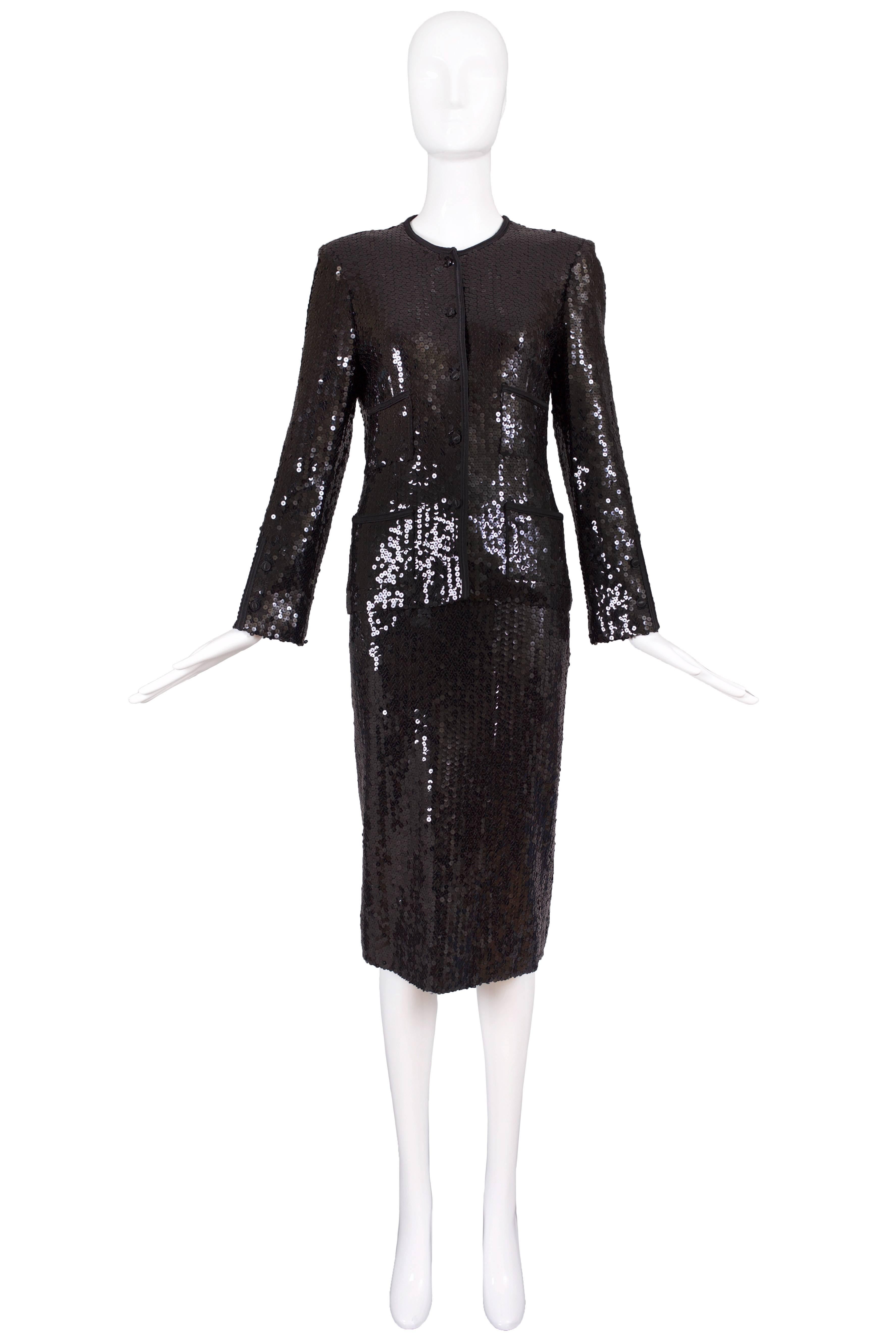 1982/1983 Chanel black sequin suit comprised of a jacket and knee-length straight skirt. Jacket buttons up the front and features four frontal pockets. Both top and bottom entirely lined in silk. Labeled Chanel. Size 40. In excellent condition with