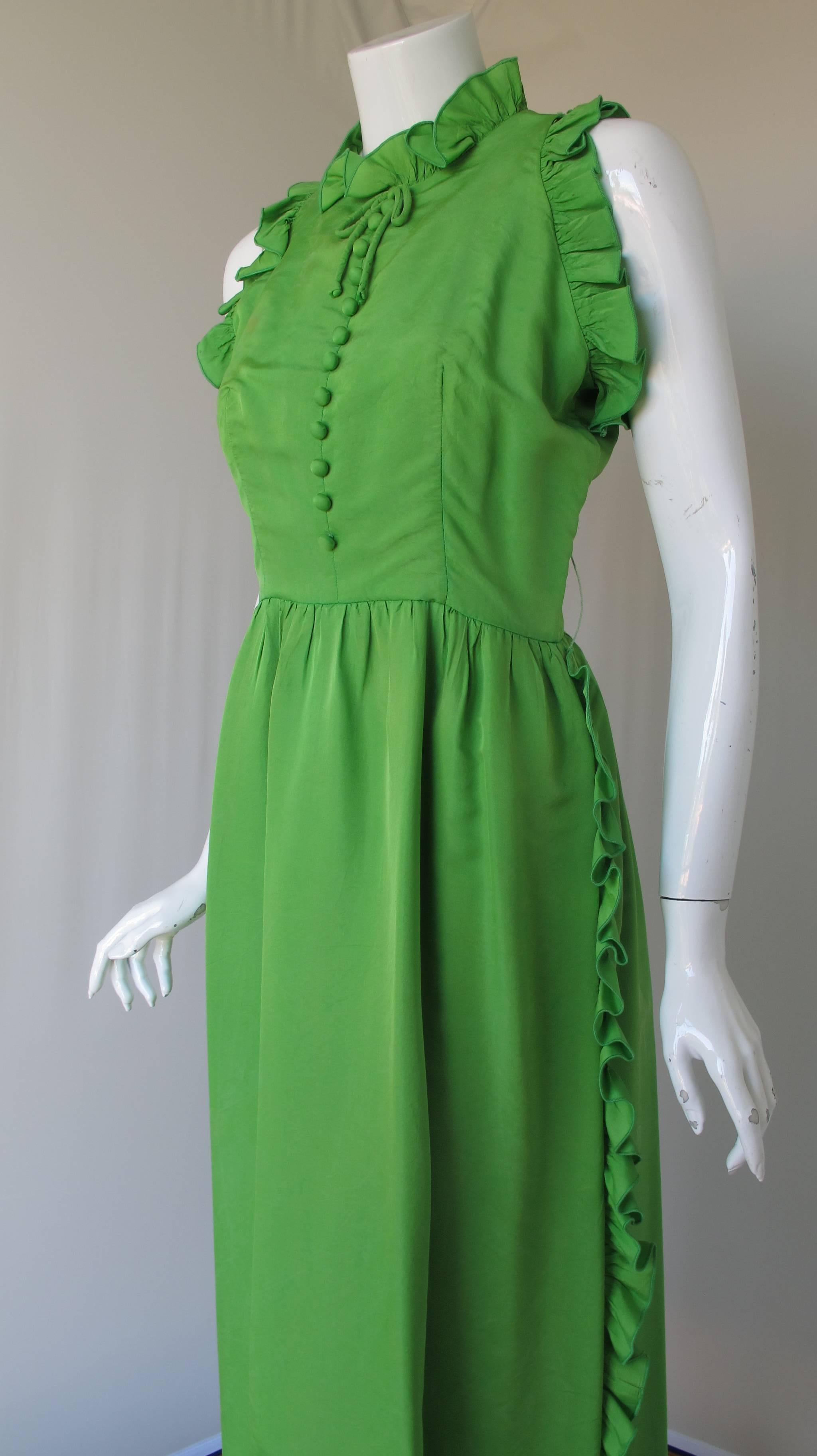 A 1970's Oscar de la Renta bright green washed silk sleeveless evening gown with ruffle detail, silk buttons and bow at the neckline. Lined at the interior. In good to very good condition with a small stain at the bodice front, missing belt and a