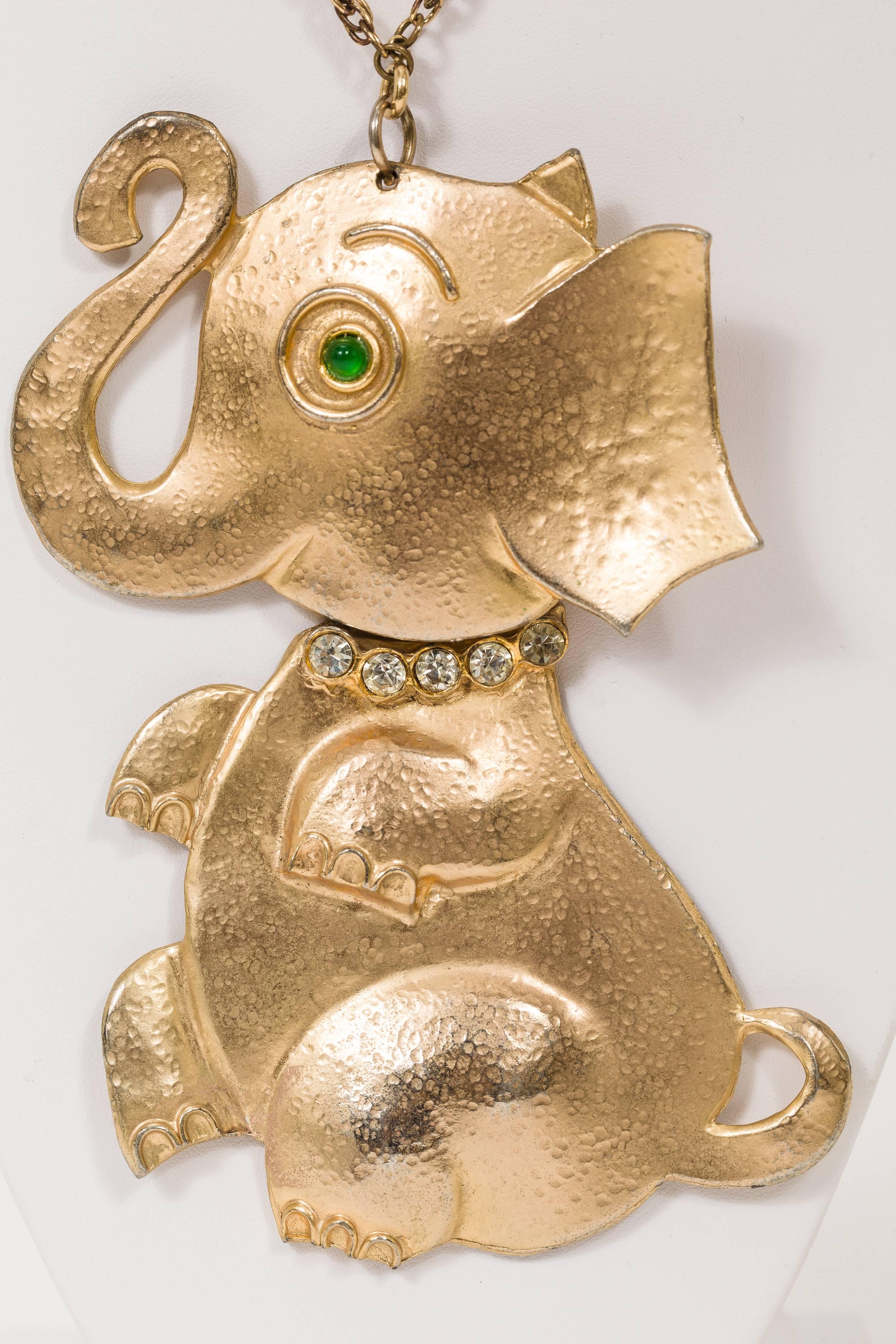 Rare vintage Hattie Carnegie goldtone elephant pendant necklace with articulated, moveable head. Elephant is decorated at the neck with a collar of rhinestones and a green cabochon stone for the eye. Stamped 