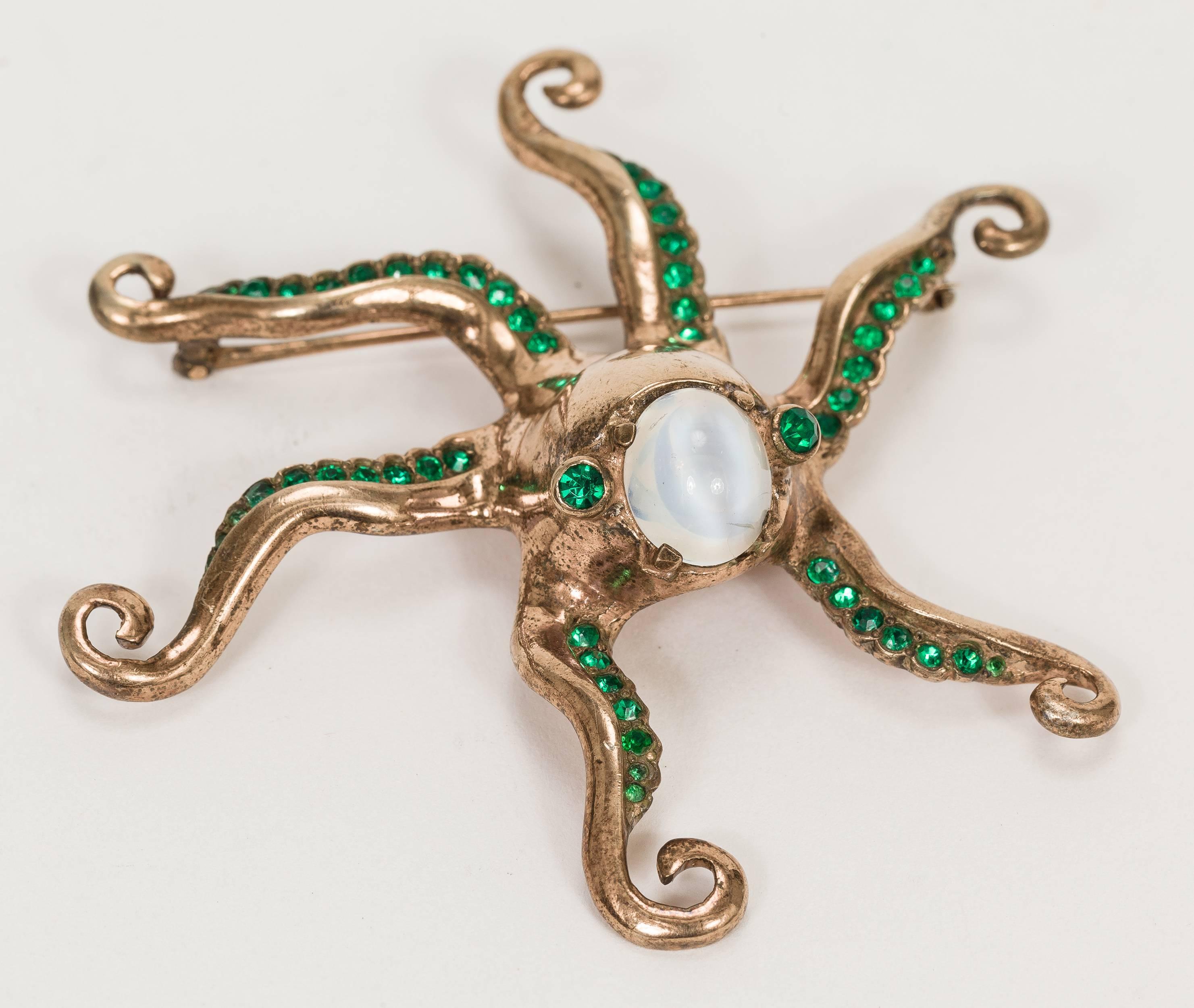 Nettie Rosenstein rose gold-plated over sterling base metal octopus pin, circa 1940. This beautiful aquatic creature has a simulated opaline cabochon head and emerald green rhinestone eyes and each of the octopus' six arms have emerald green
