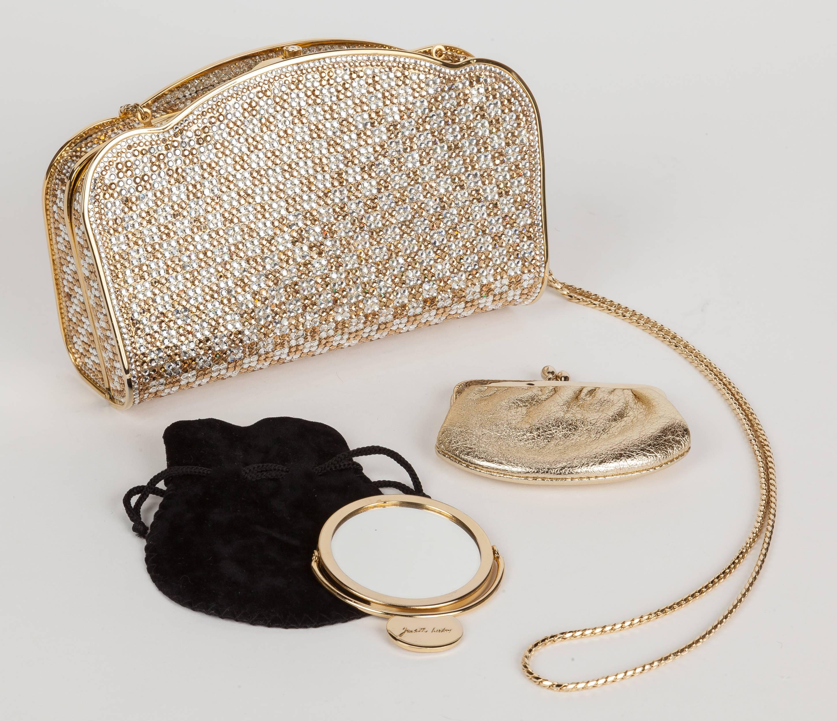 A circa 1990's Judith Leiber gold & silver/white bejeweled Swarovski crystal minaudière with gold tone metal envelope-shaped box form and curved/scalloped edges. Features a gold leather interior, gold chain shoulder strap, a bezel-set crystal push