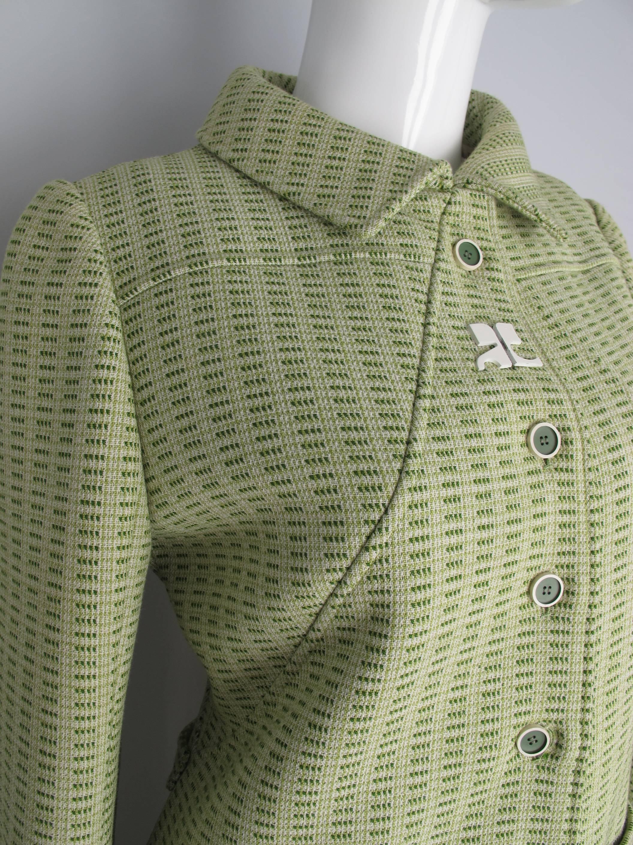 A 1970s Courreges green patterned wool blend coat with green plastic buttons and plastic Courreges logo at the front. Features two front pockets and a back band. In very good to excellent condition with the exception of the acetate interior lining