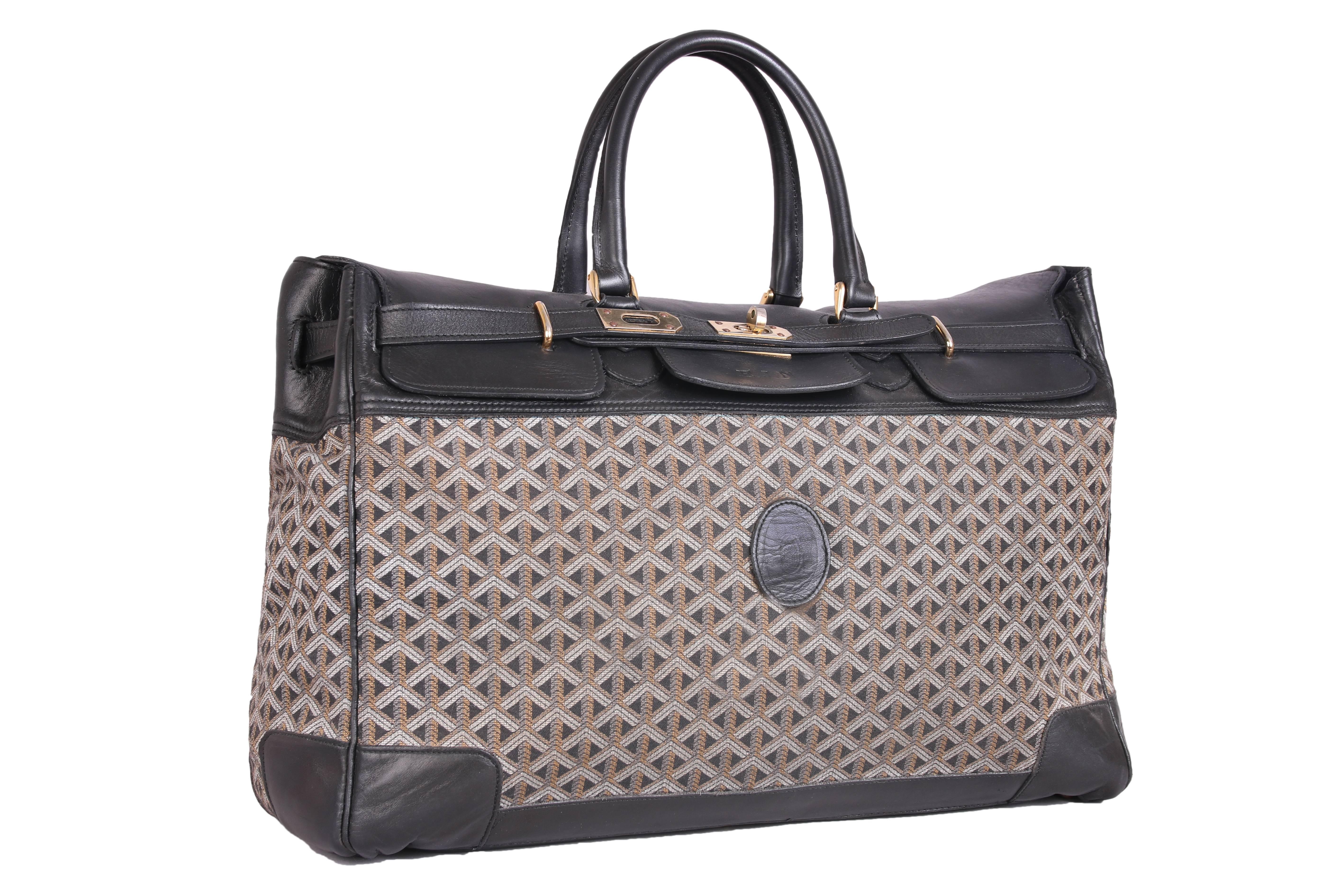 An oversized vintage Goyard travel bag with wraparound straps in the "Birkin" style." Materials are leather, metal and canvas with a creme colored canvas interior. There is an embossed monogram at the front with the initials,