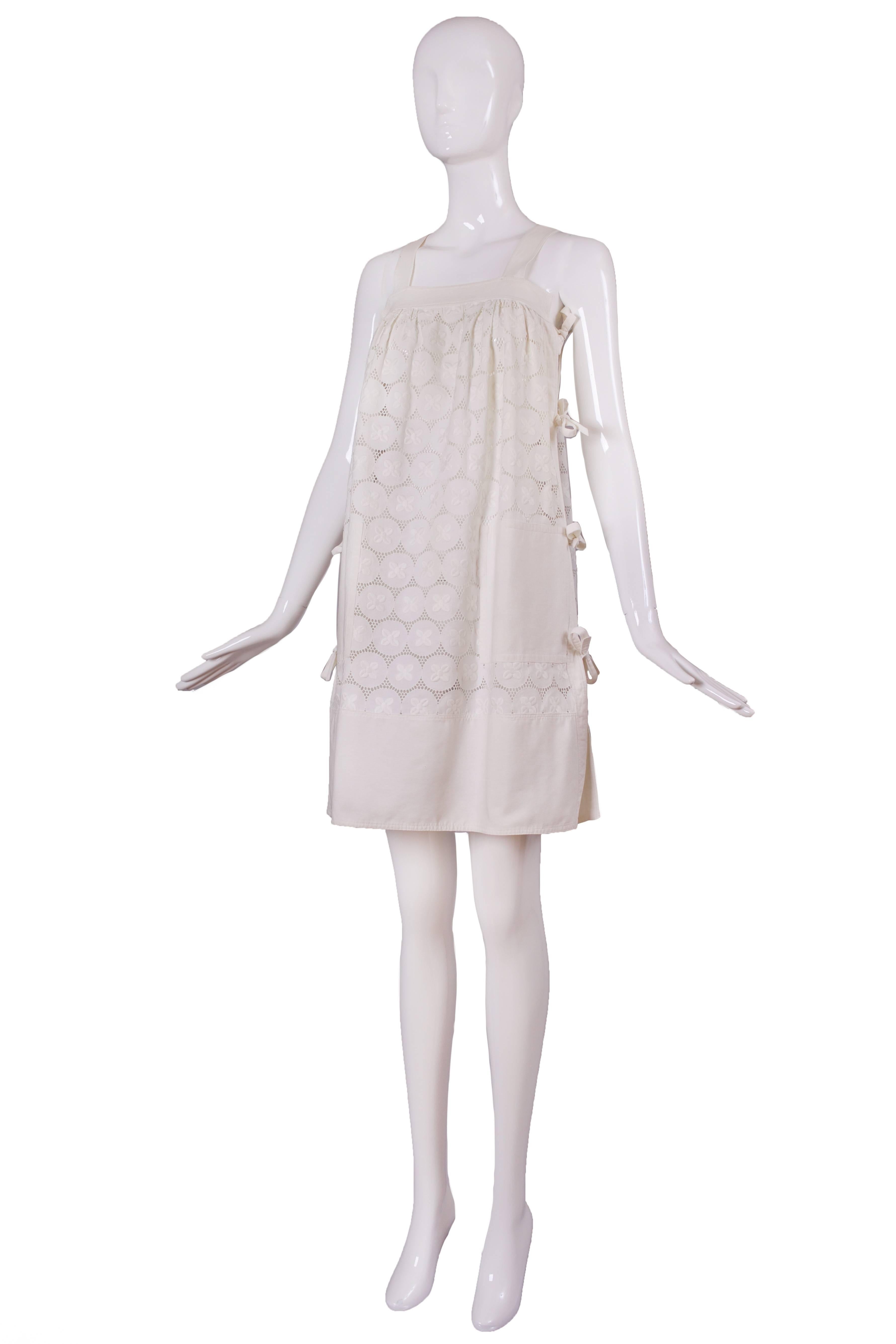 Vintage Courreges white eyelet 100% cotton sundress with a bateau style neckline. The eyelet is formed from conjoining ribbed cotton circles with an embroidered flower at the center and with crocheted lace or some form of lace in between. Each side