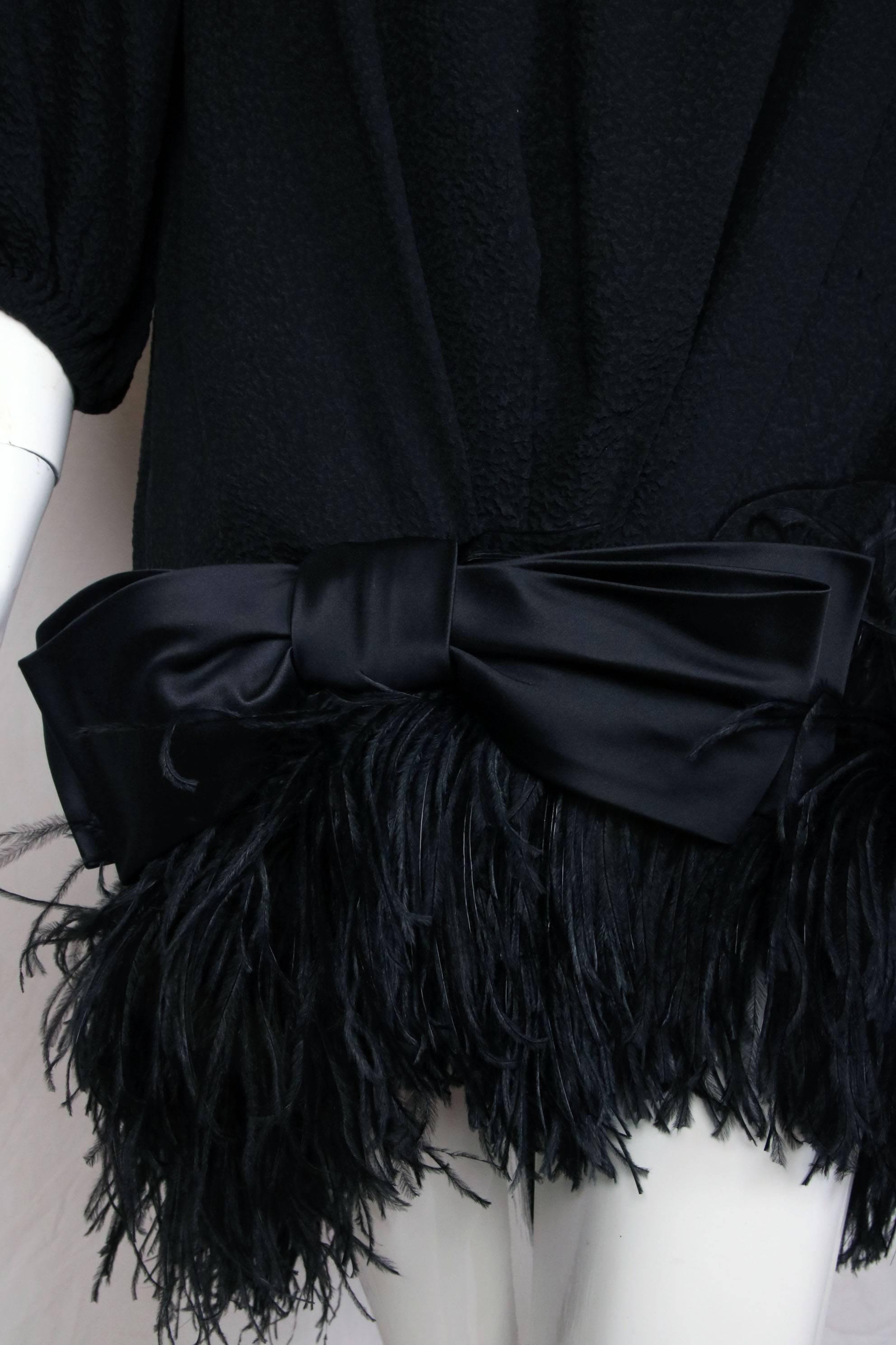Abito da cocktail anni '70 di Yves Saint Laurent in 100% seta nera con maniche a 3/4, rifiniture in piume di maribù nere e fiocco in seta nera sull'orlo. In condizioni da ottime a eccellenti, con qualche lieve scolorimento sotto le braccia. Taglia
