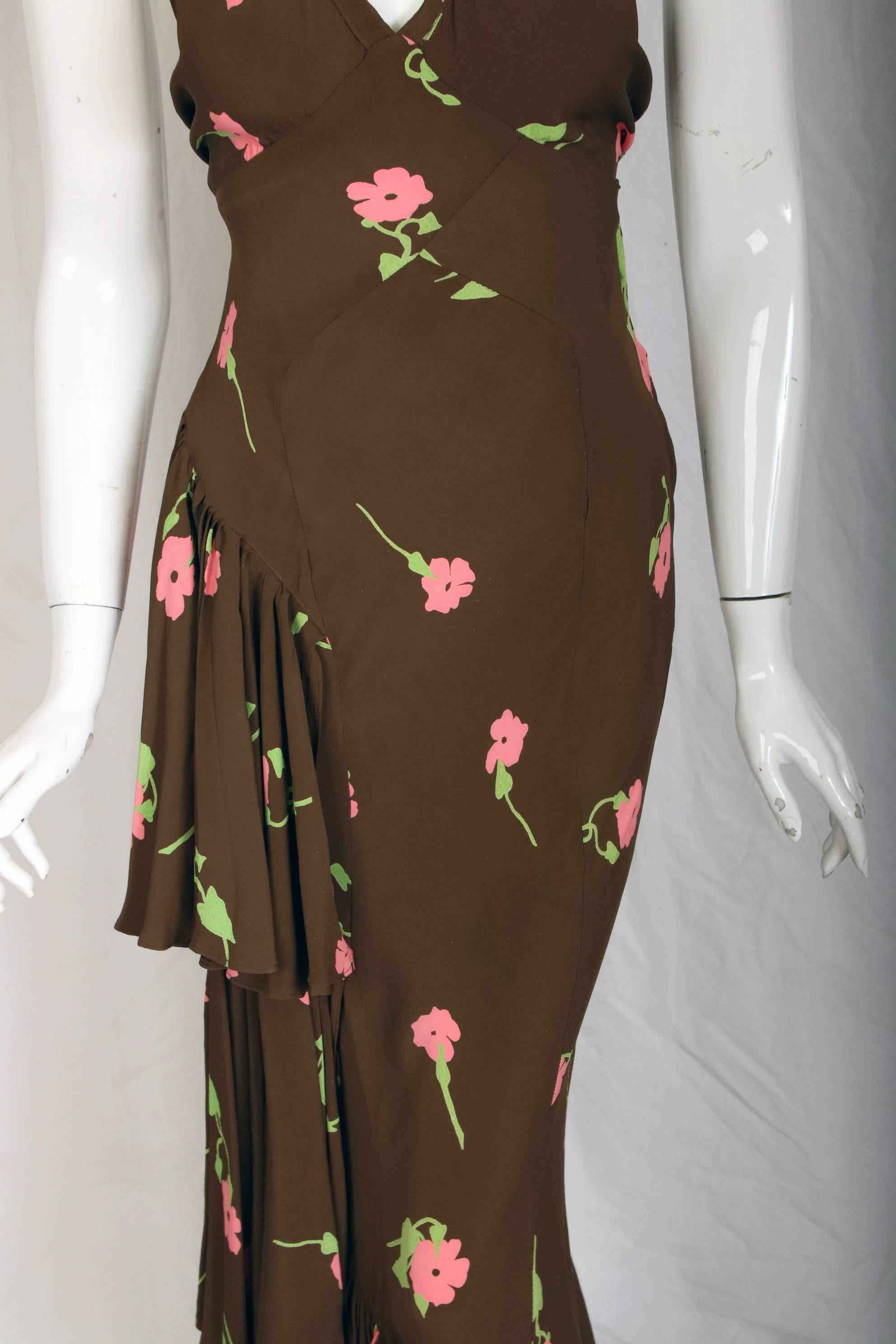 An Ossie Clark bias-cut evening gown with a Celia Birtwell floral print. Gown features one-sided ruffles down the right leg and a shoulder ruffle at the opposing, left shoulder. British Size tag 10 which would likely fit a US 2 or 4. The dress is in