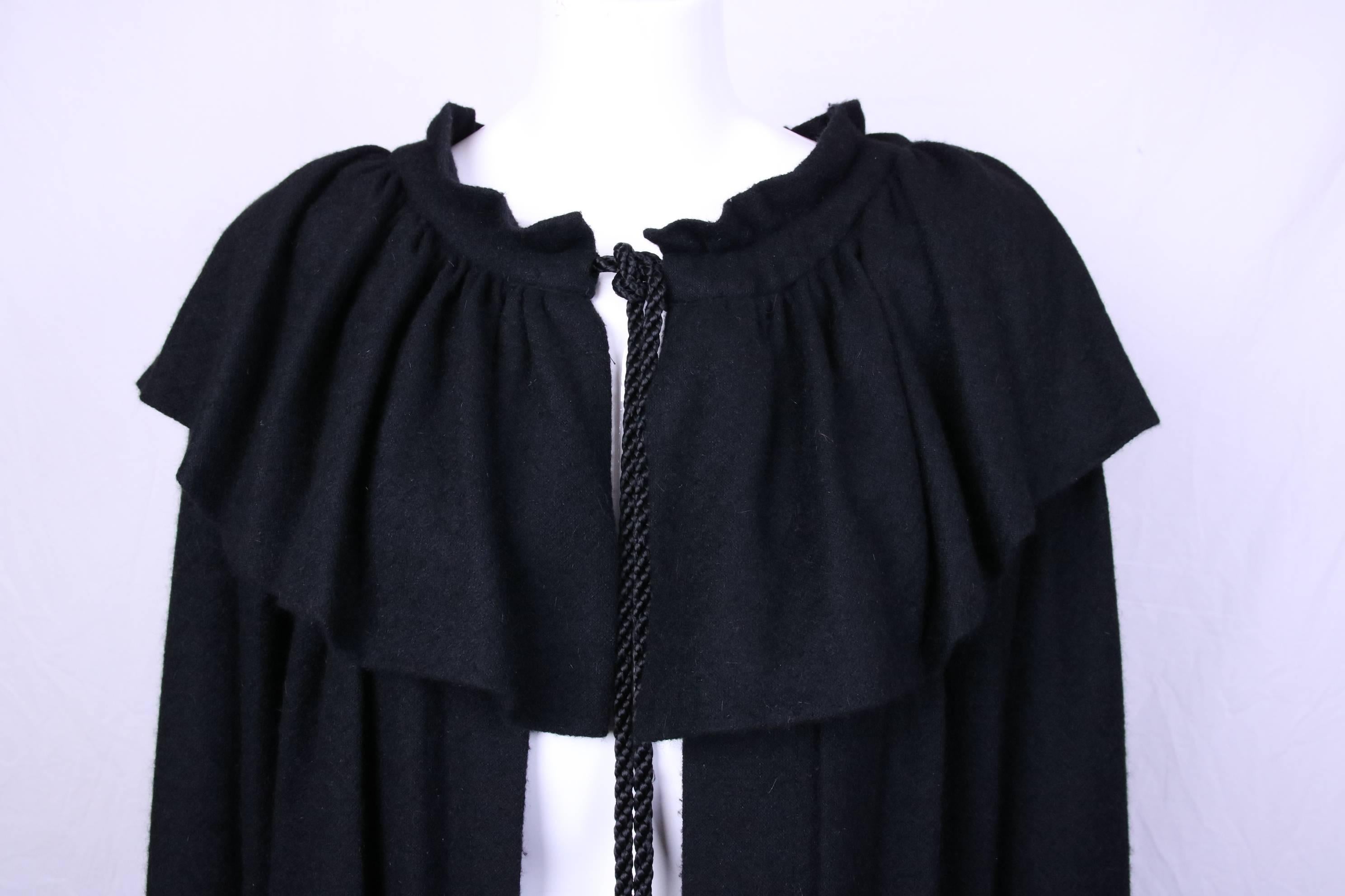 1970s Yves Saint Laurent black wool cape with ruffle collar and silk cord neck tie terminating in silk tassels. In excellent condition. There is no size tag - the cape most likely will fit most sizes from 4-10.
MEASUREMENTS:
Length - (approx.) 51