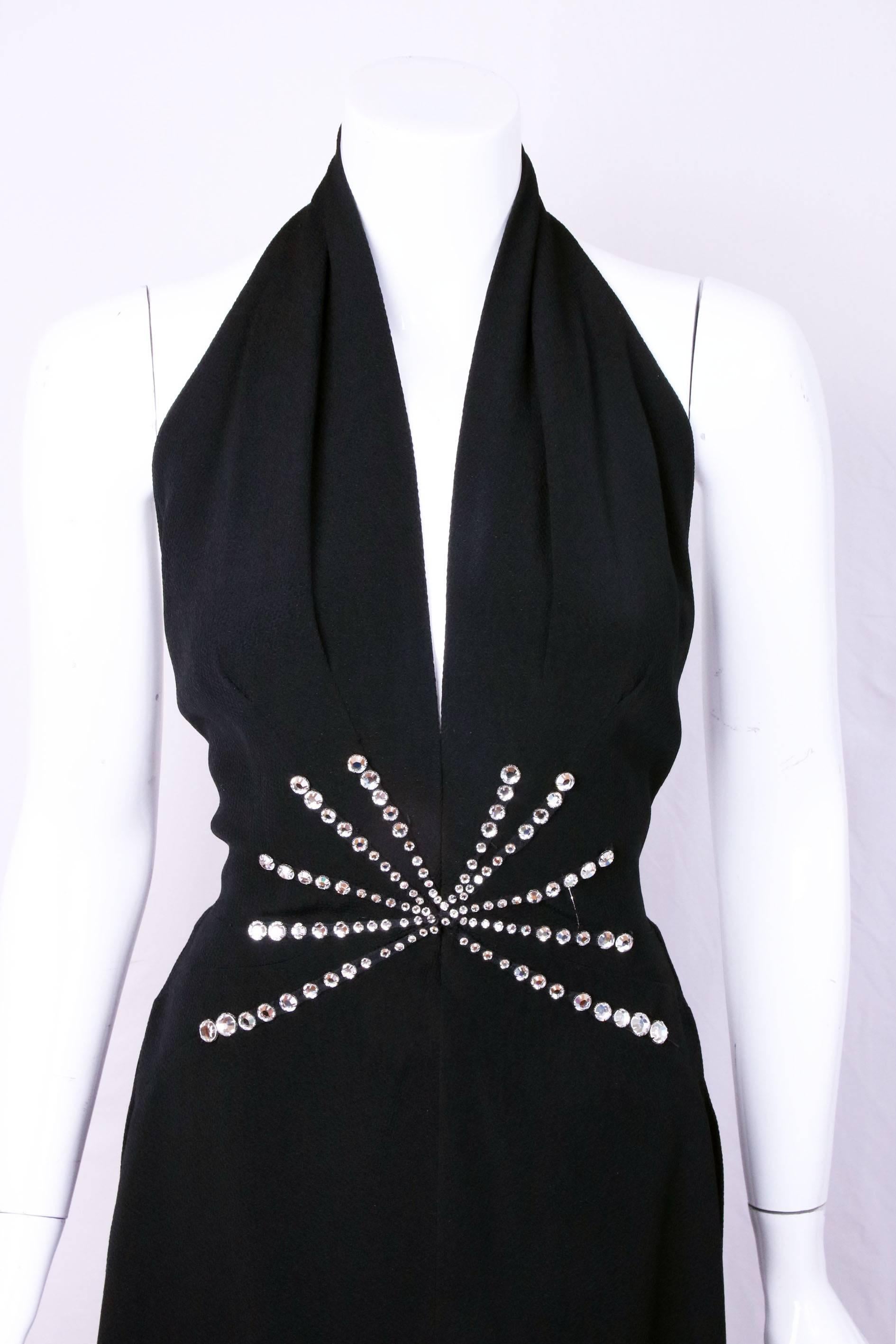 Pauline Trigere black halter neck evening gown with waterfall hem and rhinestone sunburst design. In excellent condition. No size tag so please consult measurements. 
MEASUREMENTS:
Waist - 25