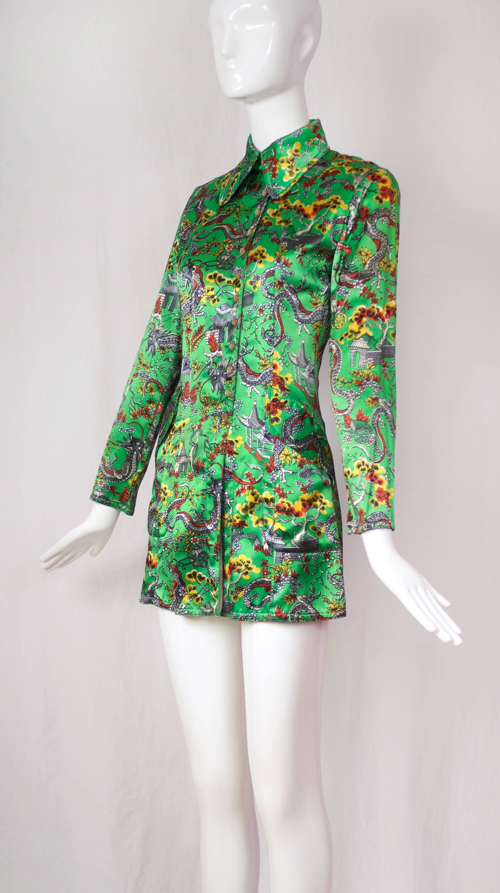 A circa 1967/1968 Ossie Clark satin rayon long jacket/tunic in green, red, yellow and gray with dragon-themed Chinoiserie print. The jacket has a structured fit with high arm holes, frontal pockets, pearlescent buttons that fasten off-center up the