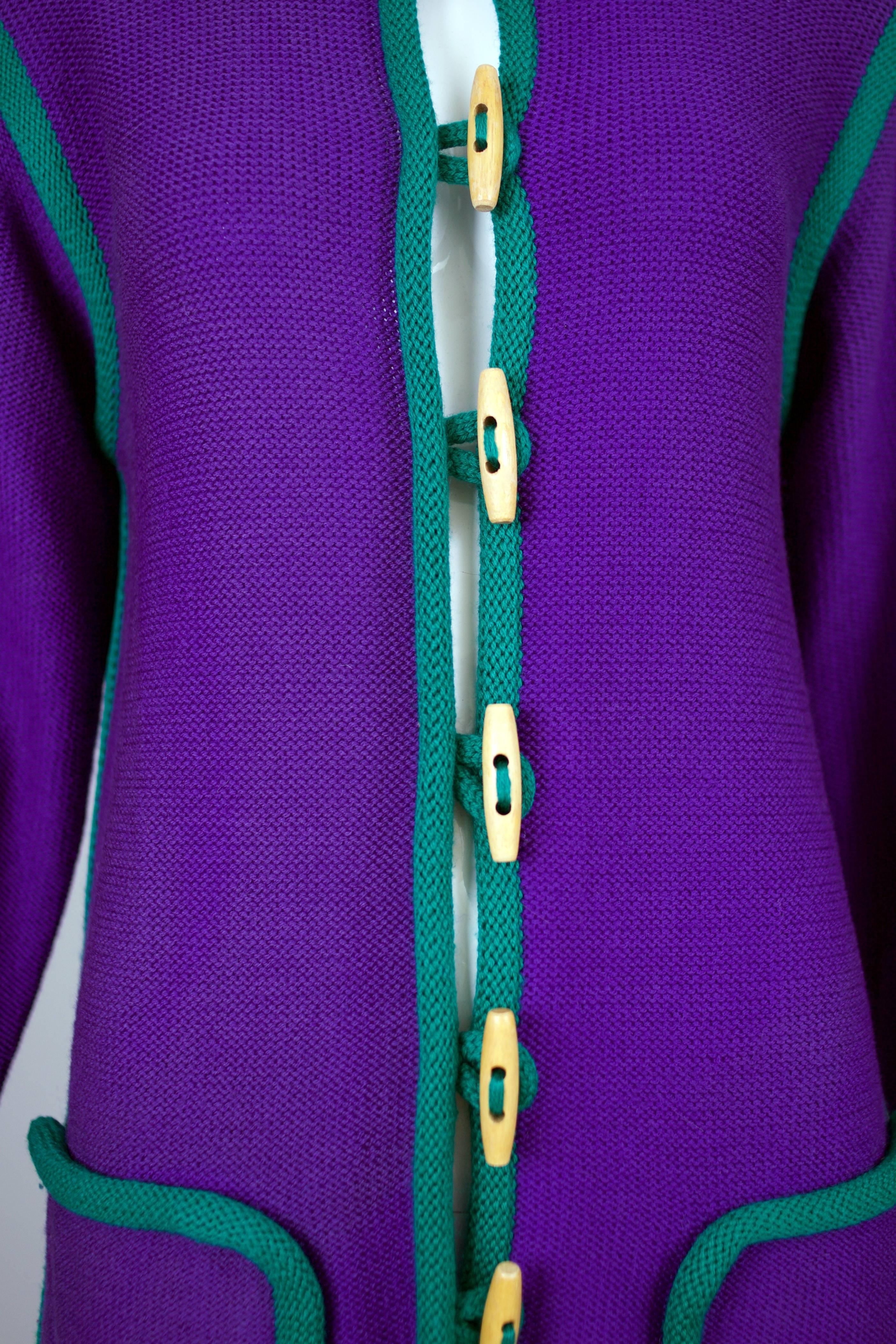 Vintage Yves Saint Laurent deep purple wool knit cardigan with green knit trim, wooden toggle buttons and a vent at each bottom side seam. Size tag M. In very good condition with several small pulls and a small nickel-sized area of discoloration on