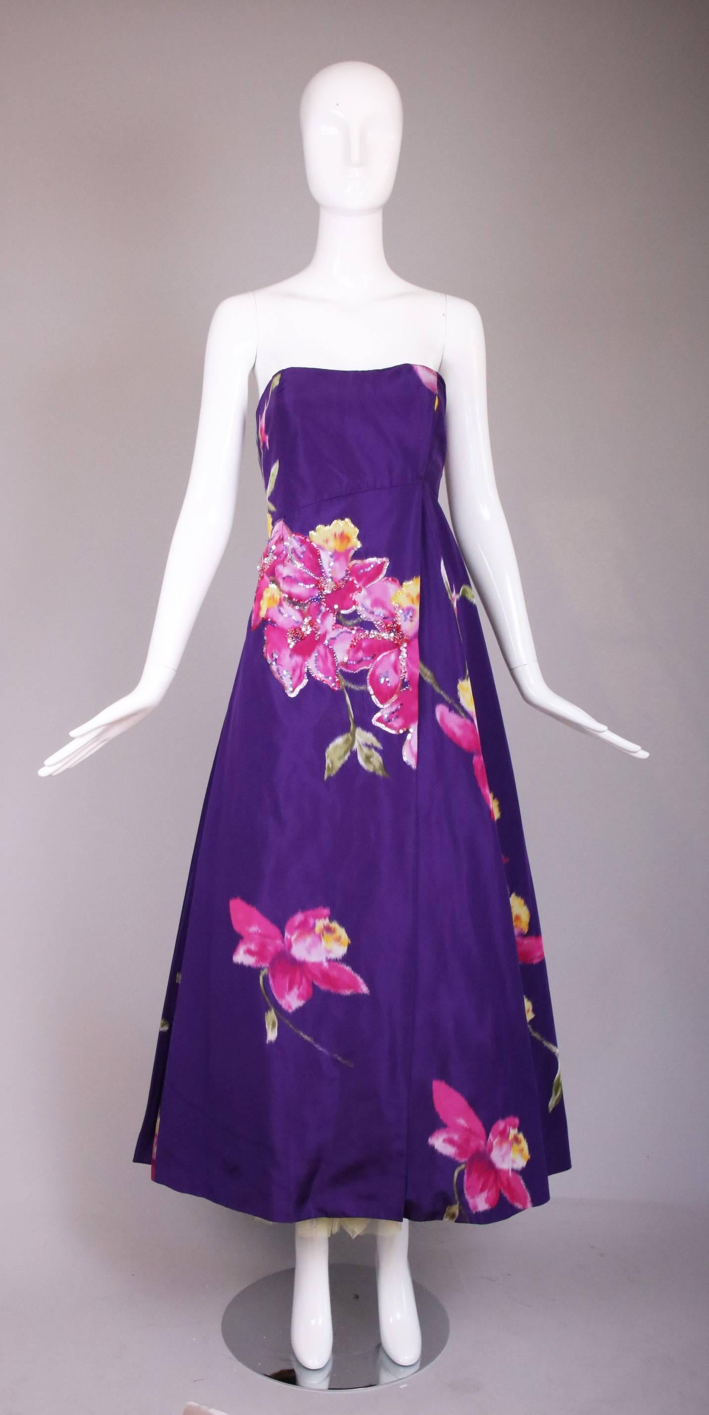 Vintage Christian Lacroix 100% silk purple floral strapless evening gown with sequin appliqués at a portion of the frontal flower clusters. Features asymmetric bodice and draping as well as layers of multicolored crinolines underneath the skirt.