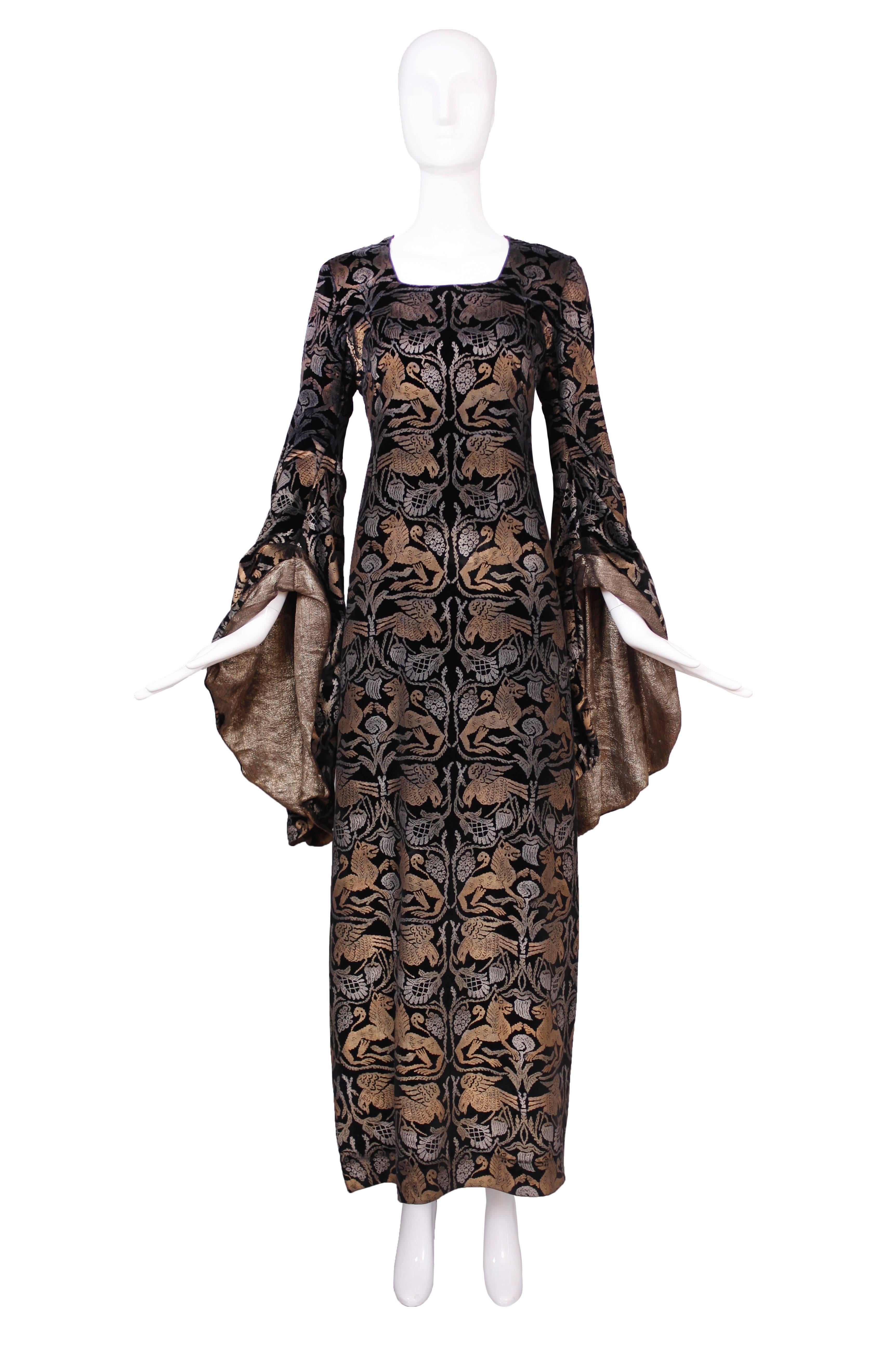Couture-Samtkleid von Maria Gallenga aus den 1920er Jahren, bedruckt mit einem schablonierten, sich wiederholenden Muster aus Silber und Kupfer/Gold, das Fabelwesen darstellt. Das bodenlange Kleid hat dramatische Trompetenärmel mit goldenem