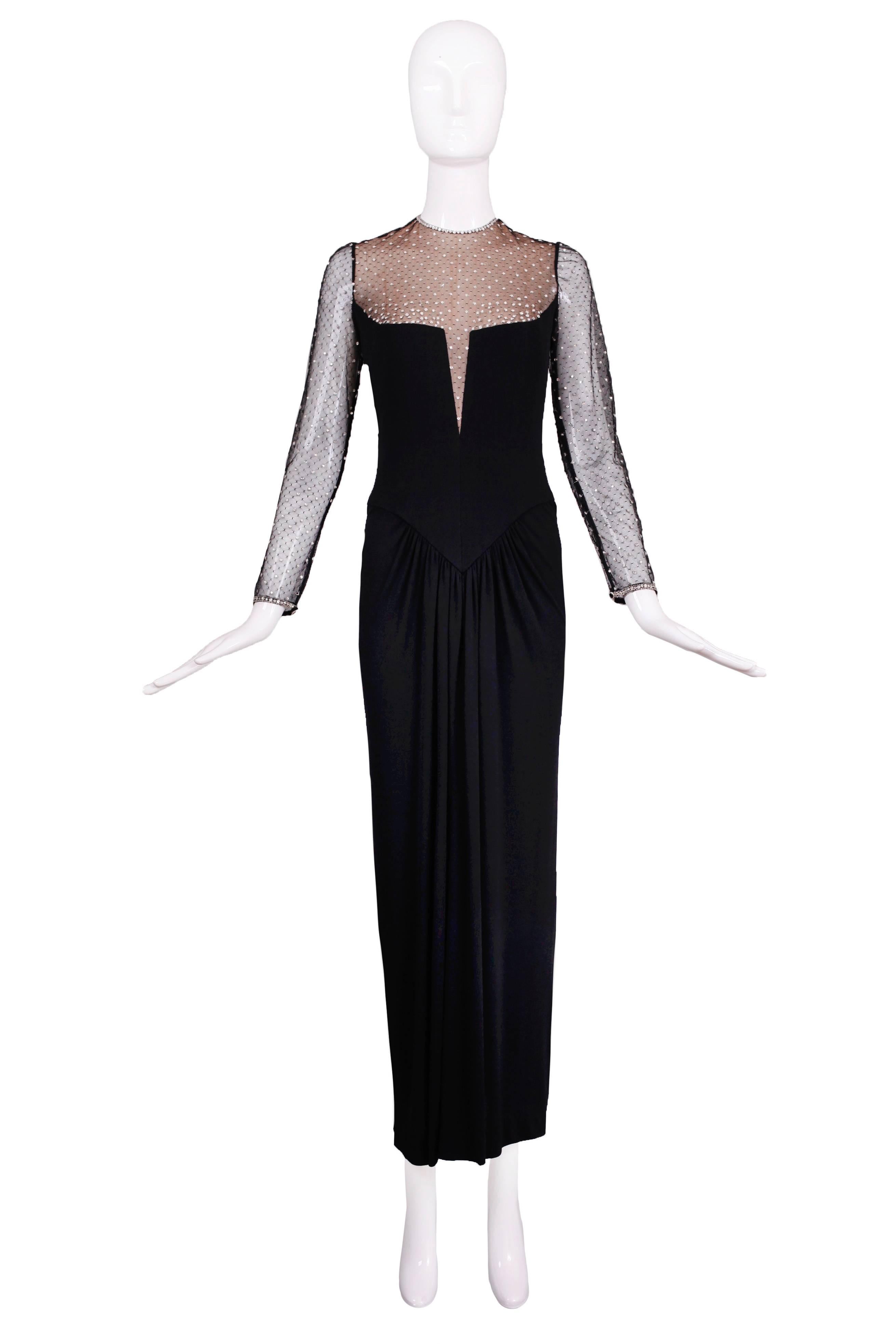 This classic 1980s Bob Mackie black illusion gown is made from silk jersey and chiffon-lined black netting with rhinestones. With its dropped waist and pleating - it is an incredibly flattering silhouette. Great little details such as rhinestone