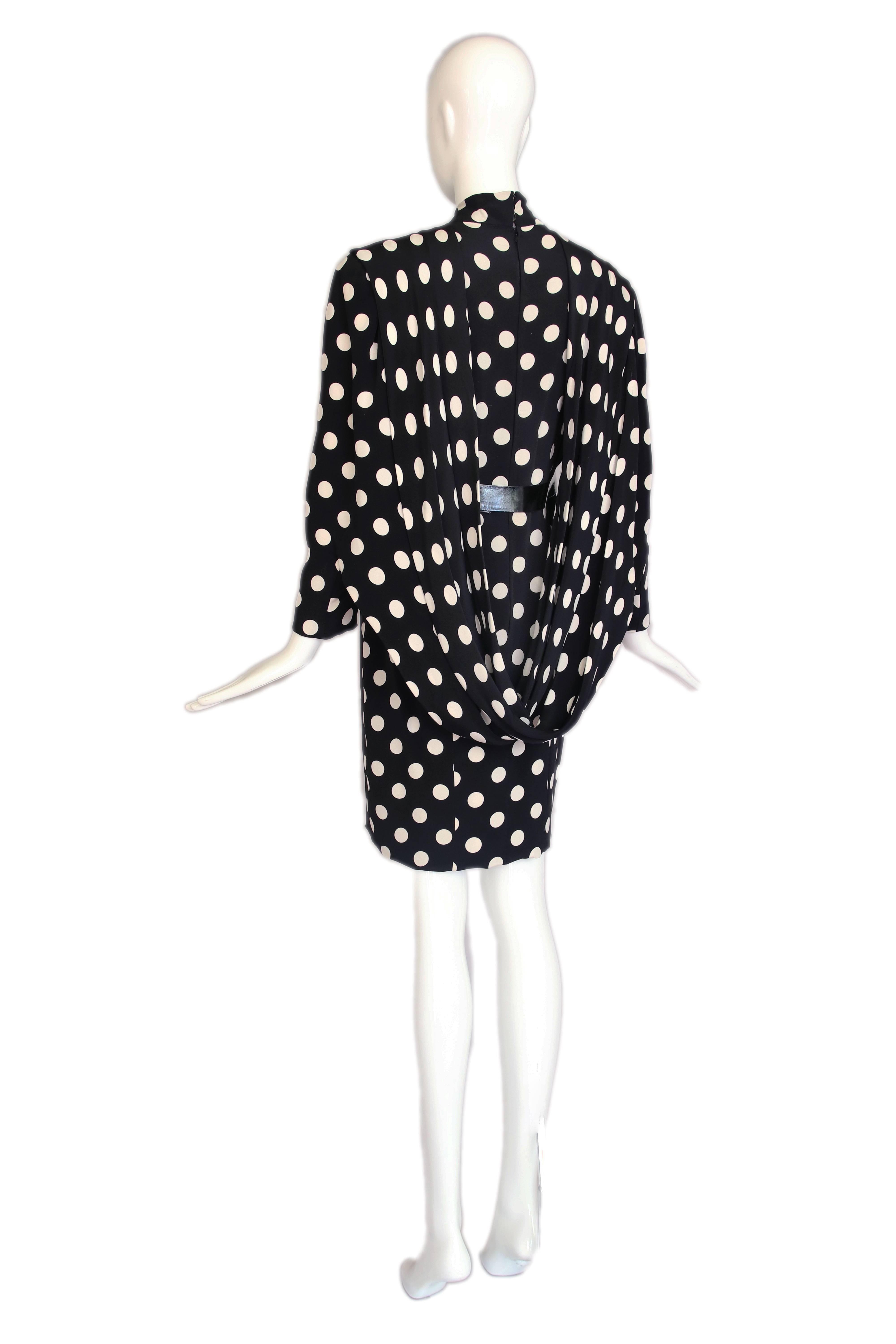 1987 Pierre Balmain haute couture black and white silk polka dot cocktail dress with patent leather belt and fabric drape at back shoulder that attaches at sleeves for dramatic effect. Attached is original editorial. In excellent