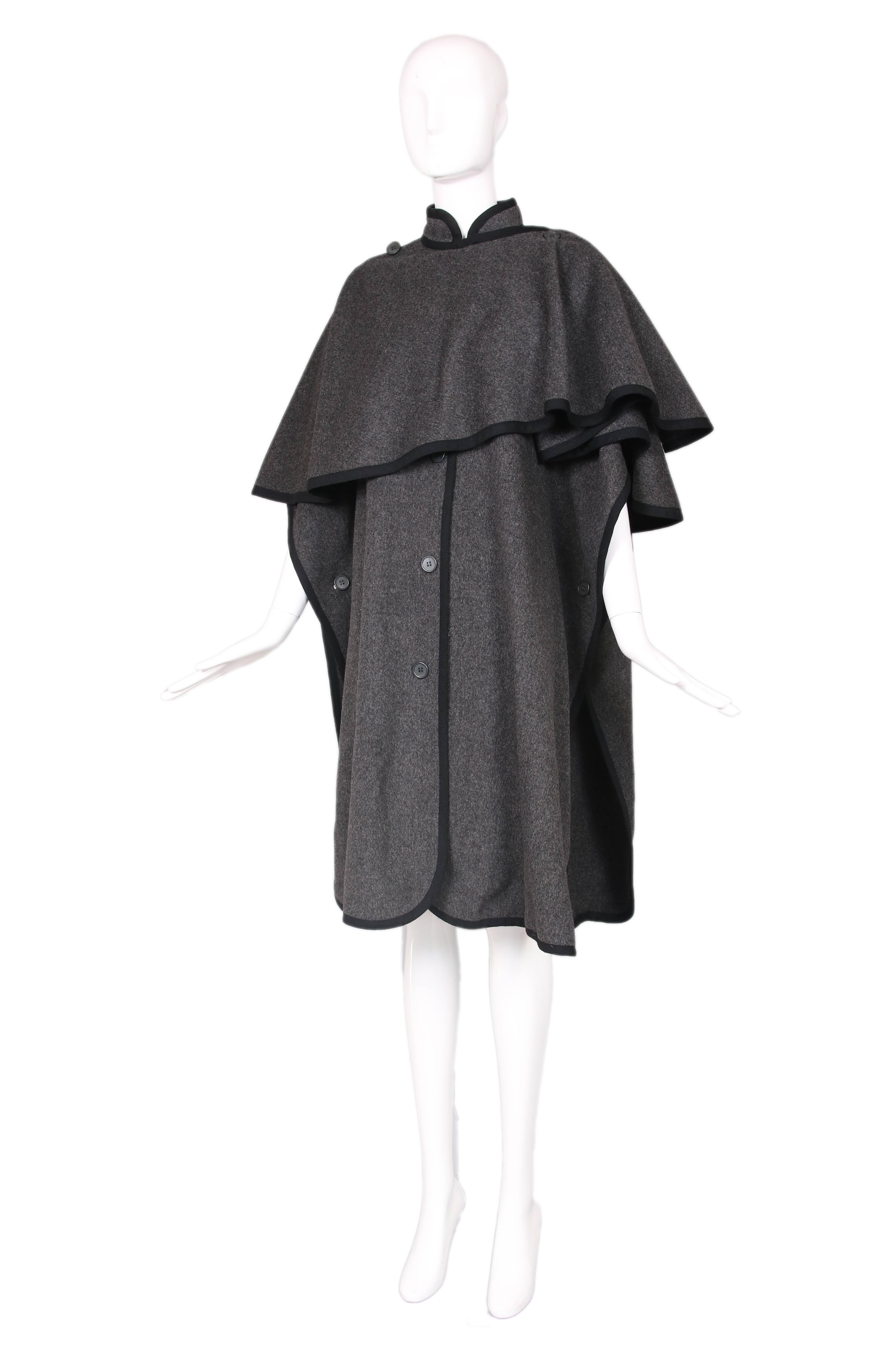 Yves Saint Laurent grey wool cape with black trim and front buttons. Oversized collar can be worn multiple ways. In excellent condition. Size EU 36.
MEASUREMENTS:
Length - 42