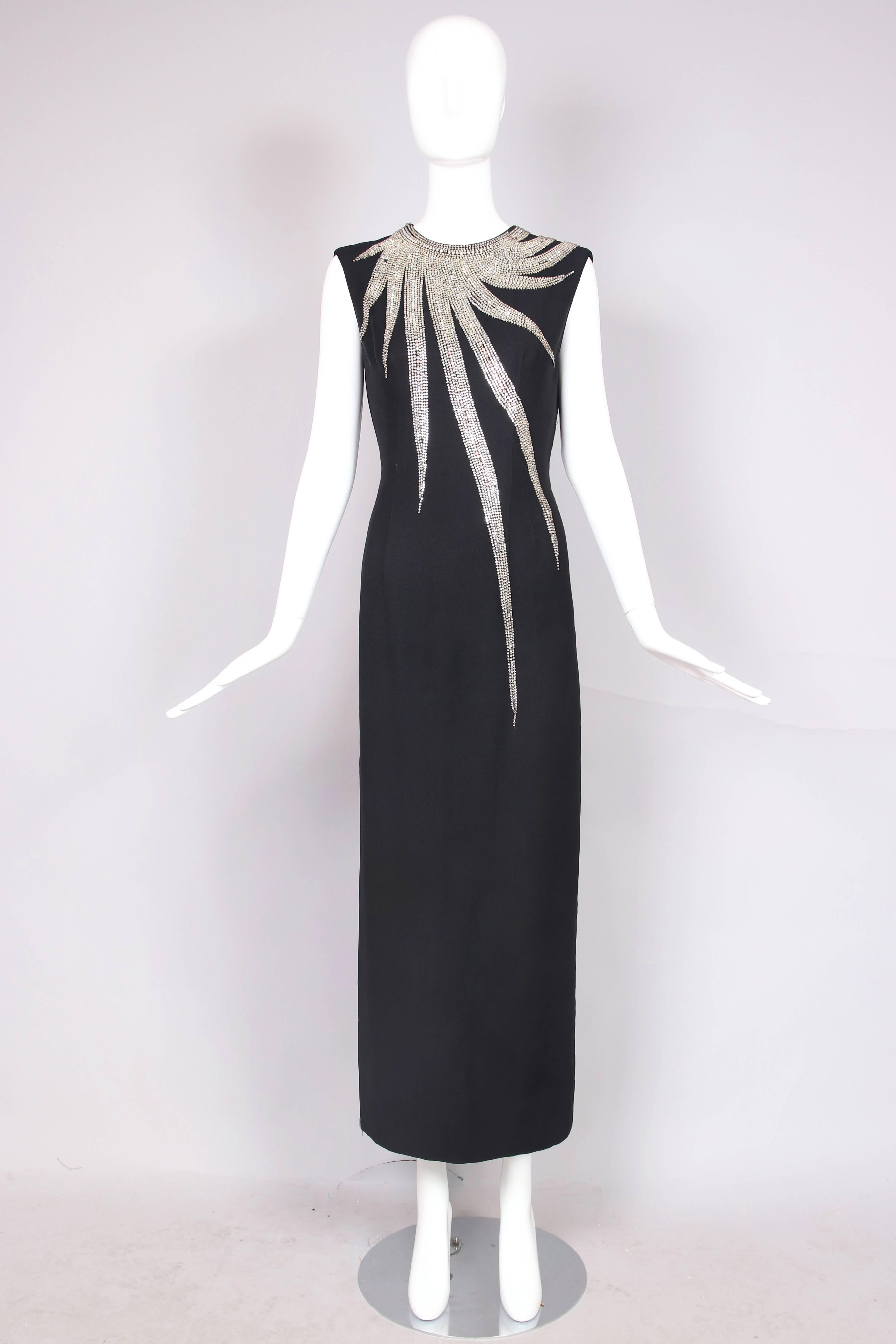 1960's Mr. Blackwell black crepe sleeveless evening gown with frontal asymmetric jeweled sunburst design detail and with slit at back hem. Fully lined. In very good condition with scattered bead loss, some light and some more noticeable - a tailor