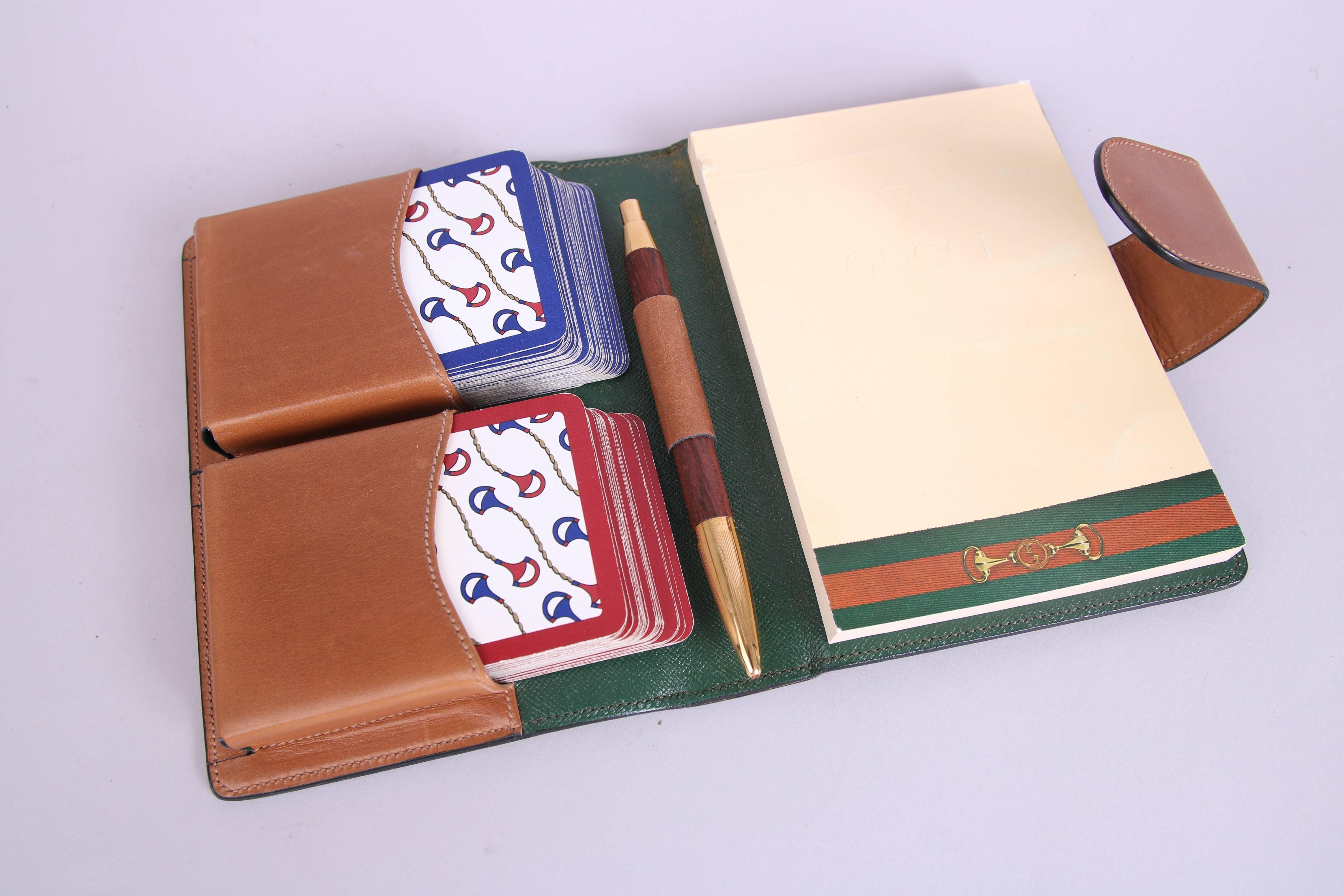 1970's Gucci caramel leather bound snap closure playing card set with green leather interior. Features a slot for removable fliptop notepad embossed with Gucci logo and crest, as well as two full decks of cards in red, blue, and gold Gucci horsebit