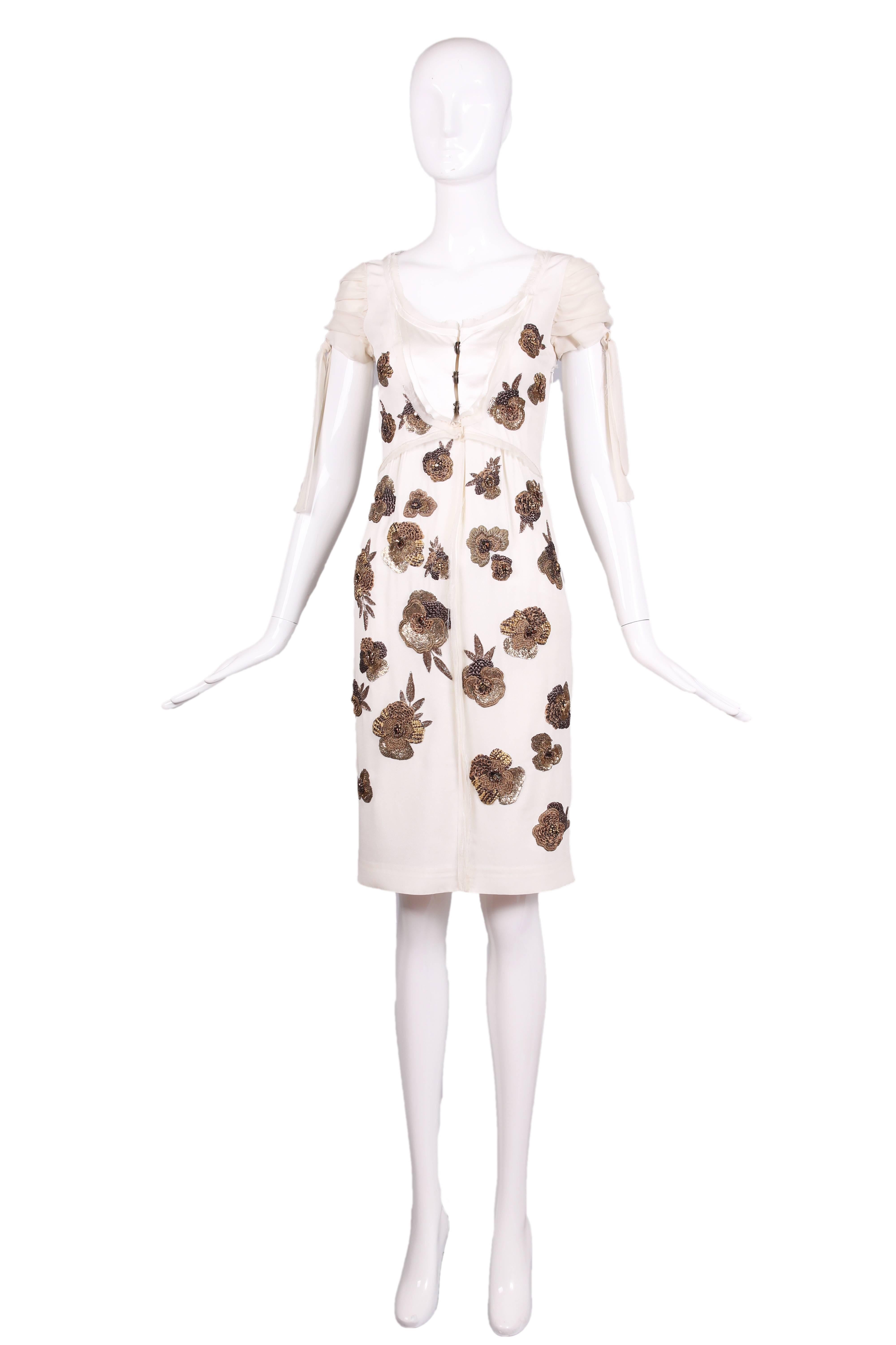 Dice Kayek white silk dress w/three button snap closure at bust, scoop neck, and cap sleeves that tie. Dress features bronze beads and sequin embroidered floral design and an unfinished hem with intentional loose threads. In excellent condition.