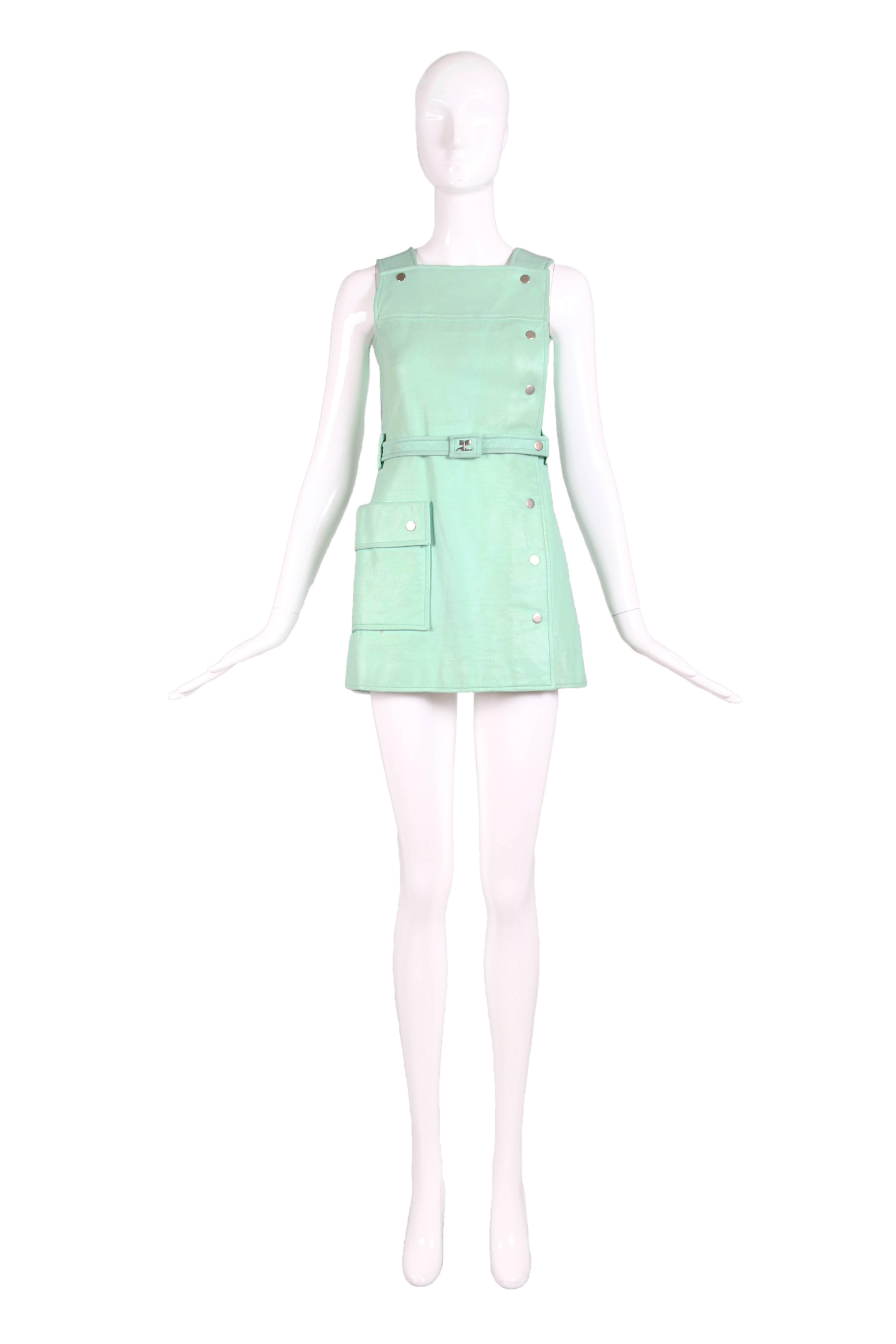 1970's Courreges aqua blue vinyl mini pinafore dress with silver metal snap closures, single side pocket, and belt with Courreges logo at center. Fully lined. In good vintage condition - mark at front that is hidden by the belt, and two minor