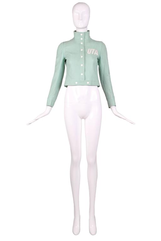 Ca. 1973 Courreges pale green vinyl cropped jacket with white metal snap closure, featuring white lettering "UTA" at front. Originally this was a flight attendant uniform for an airline, now defunct, call UTA. In good vintage condition