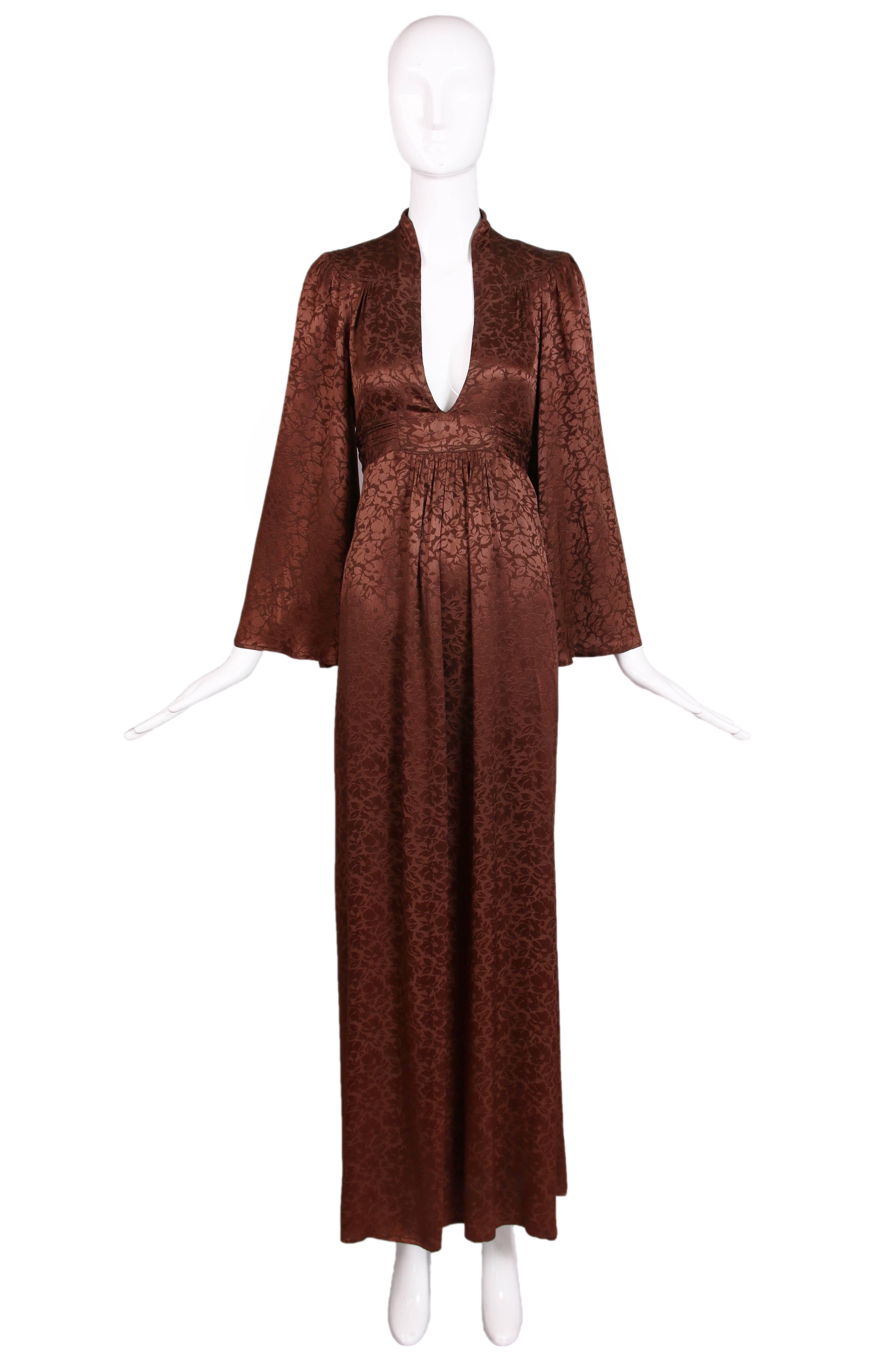 1970's Ossie Clark for Radley brown silk damask graduation dress with plunge neckline, attached waist ties, and flared sleeves.  There are gathers at shoulders and at empire waistline. The silk damask fabric has a floral pattern all over. In