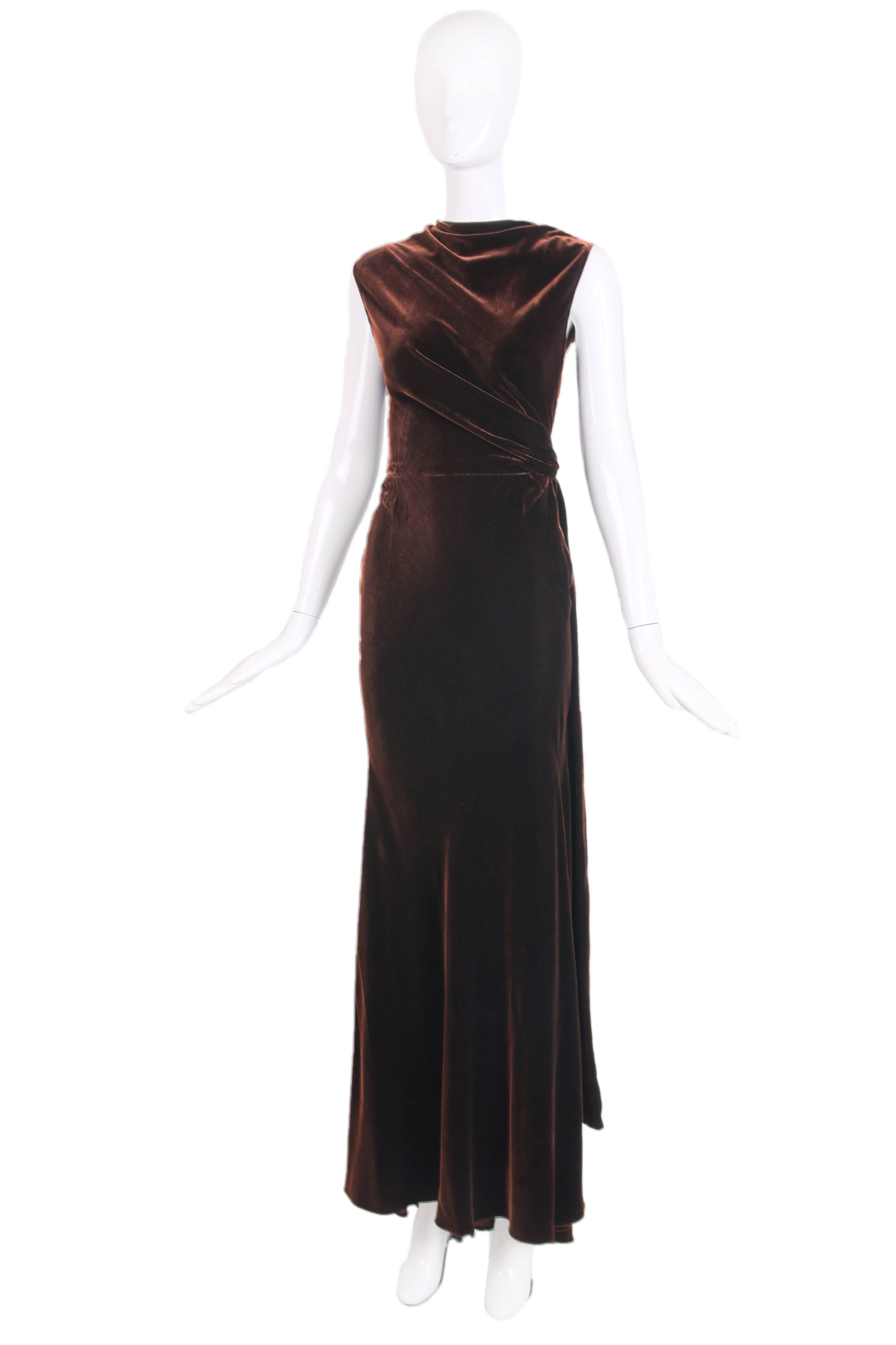 Circa 1990 Alaia couture evening gown cut in a draping grecian style. The color is a deep copper brown in a liquid silk velvet. There are classic Alaia seam detailing around hip and bottom area and a long side-tying sash that falls to the hem.