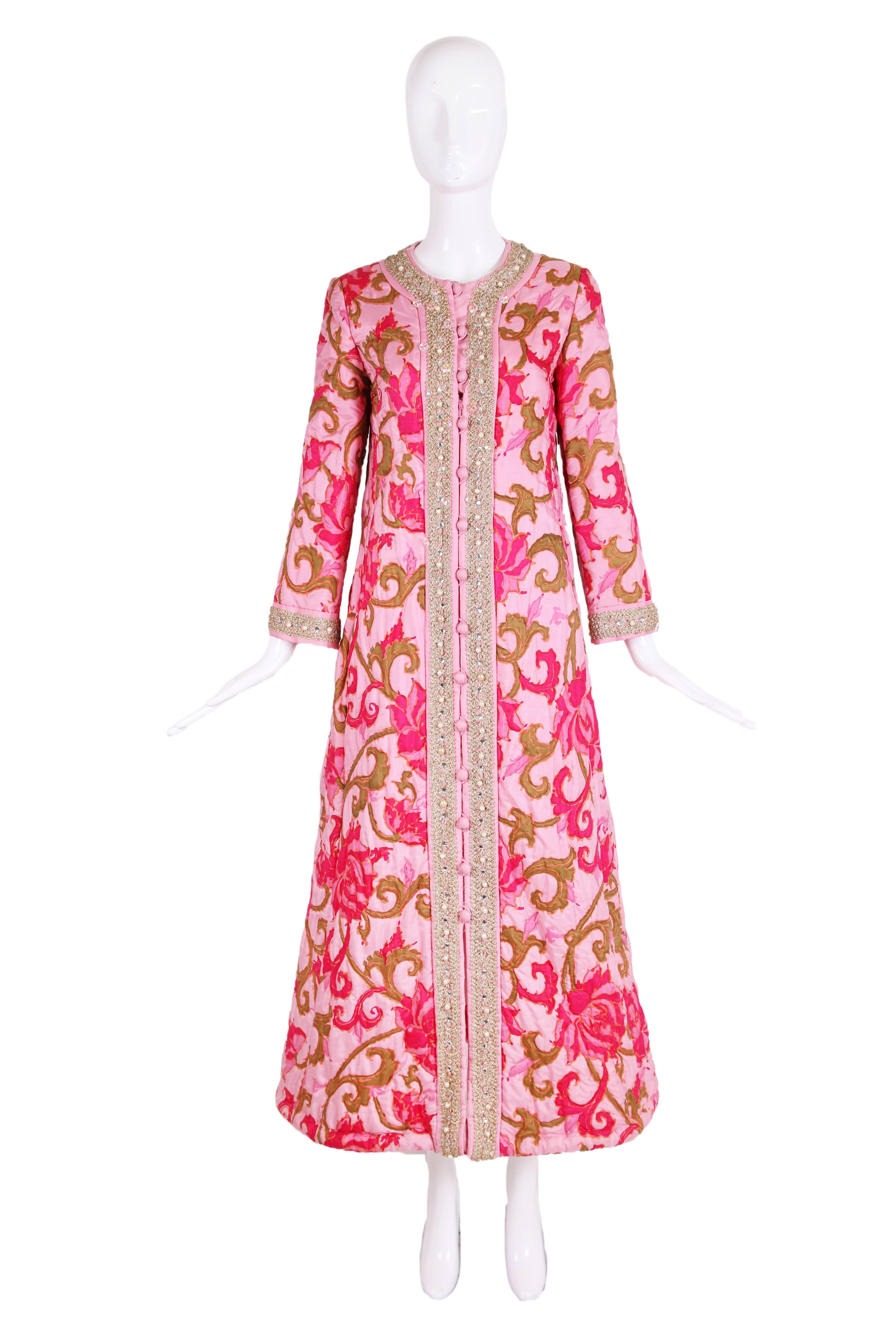 1970's Malcom Starr quilted house coat featuring an abstract floral print in shades of pink, orange and olive green. There is gold appliqued trim with white pearls, silver beads, and iridescent flower-shaped beads at center front trim, collar and