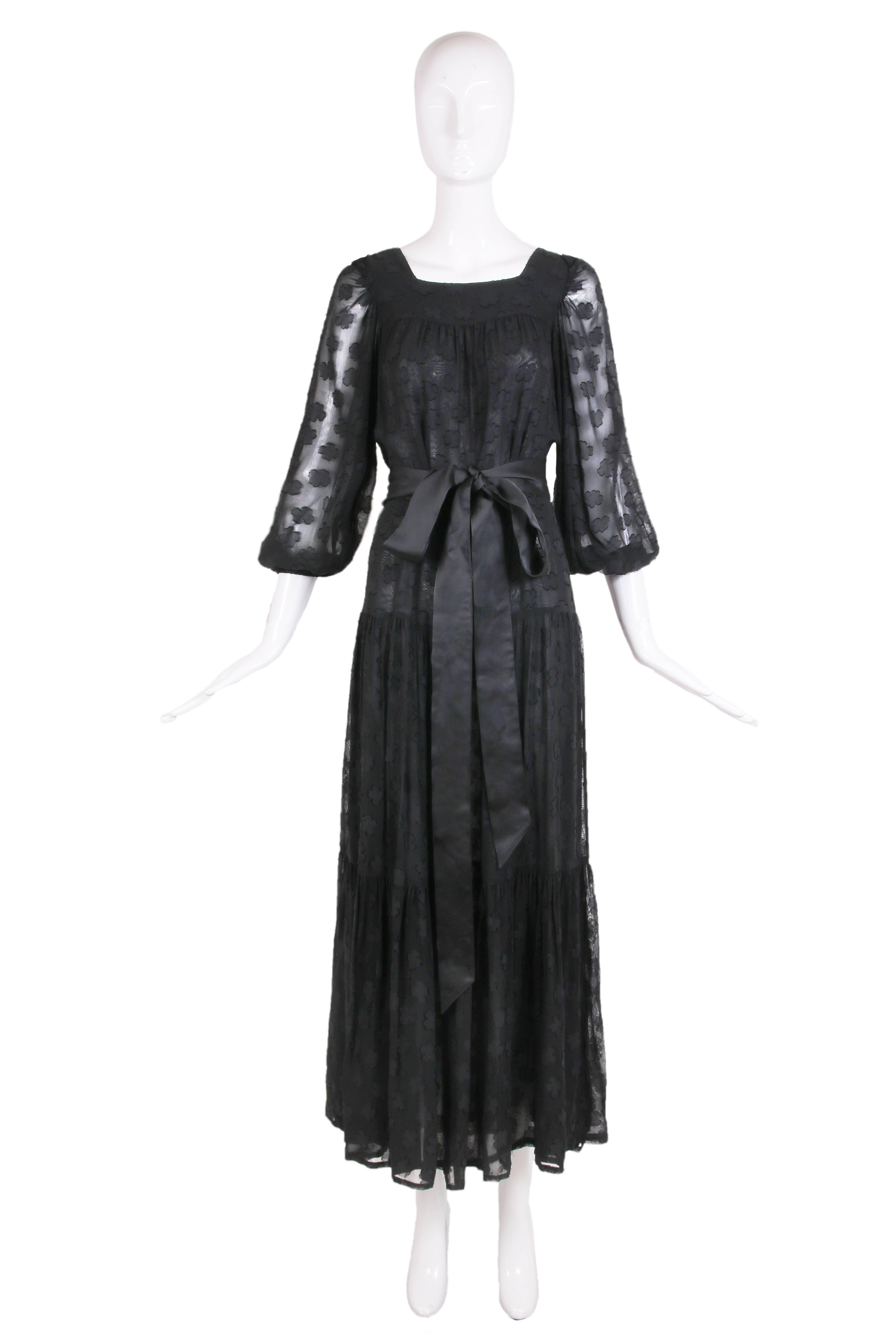 1980 Yves Saint Laurent black maxi dress with an abstract floral slightly raised pattern throughout, square neckline, tiered full skirt and sheer 3/4 sleeves. Dress is lined at the interior with black fabric so that only the sleeves appear to be