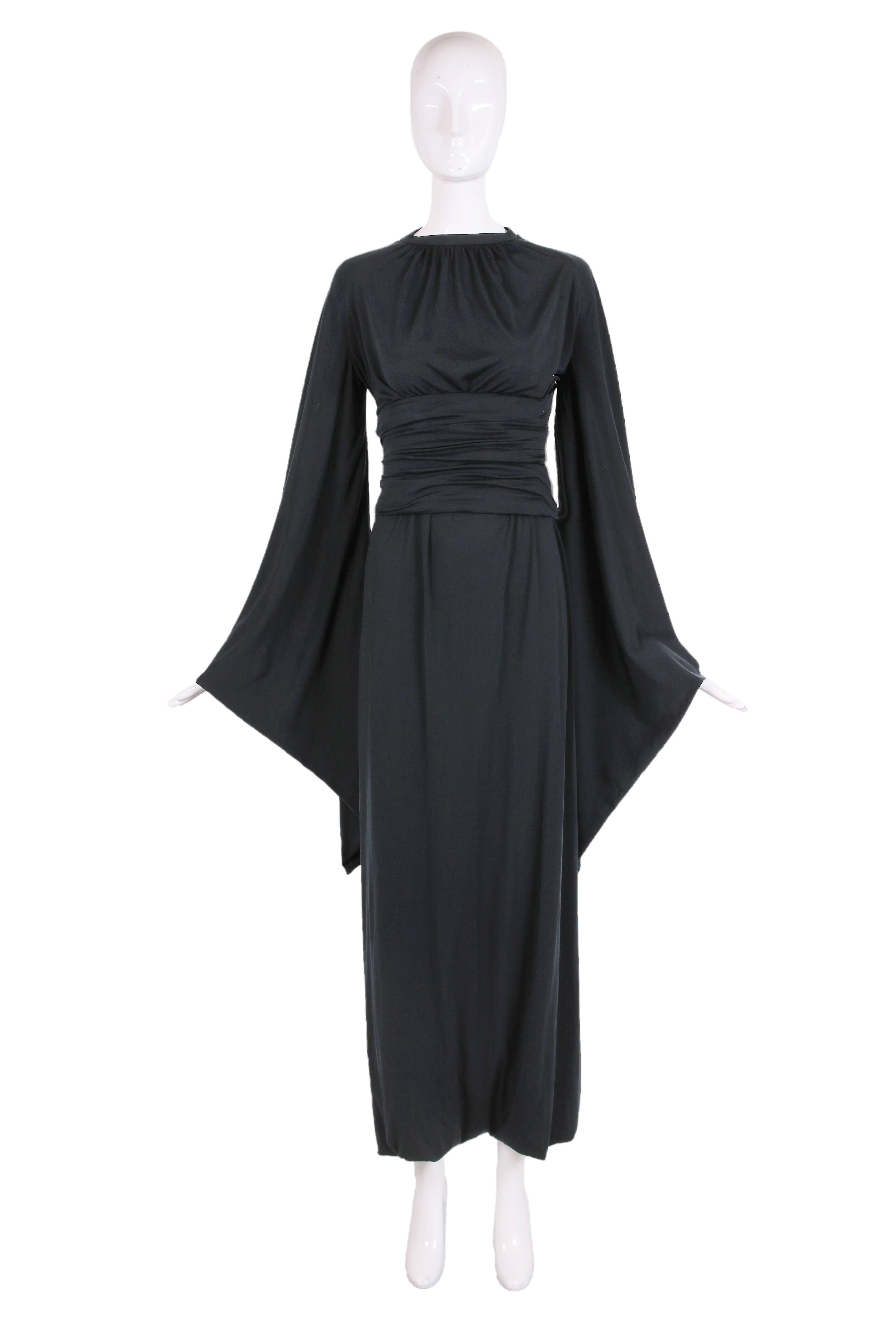Ca.1977 Pierre Cardin black jersey harem dress with pagoda sleeves and attached belt. The dress is actually sewn closed at the hem with two openings for either leg. In excellent condition with some very tiny abrasions to the jersey fabric scattered