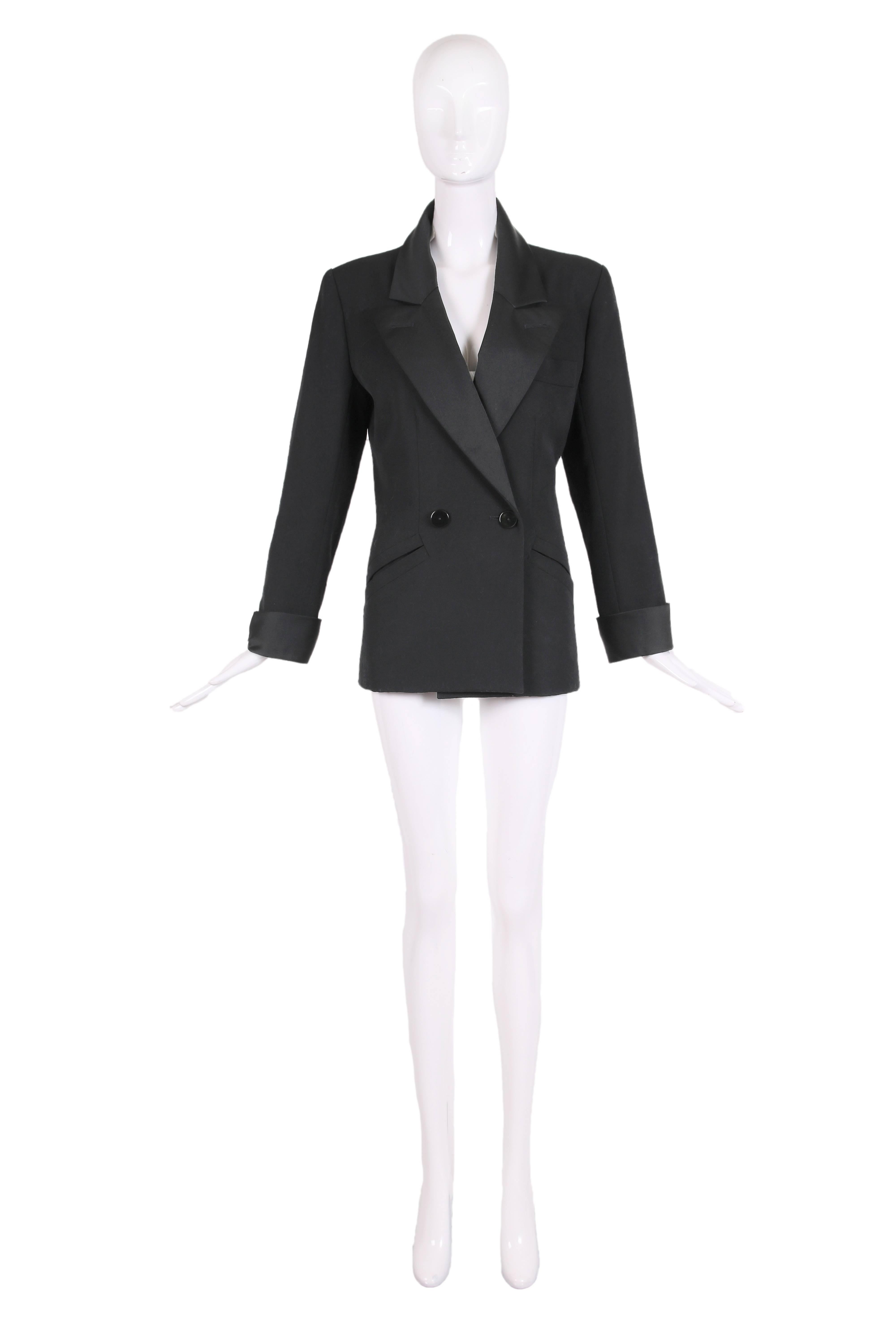 Vintage Yves Saint Laurent black tuxedo jacket with satin lapels and cuffs. The jacket is double breasted with two frontal button closures and a single decorative button at each sleeve cuff. The front also has one handkerchief pocket at the breast