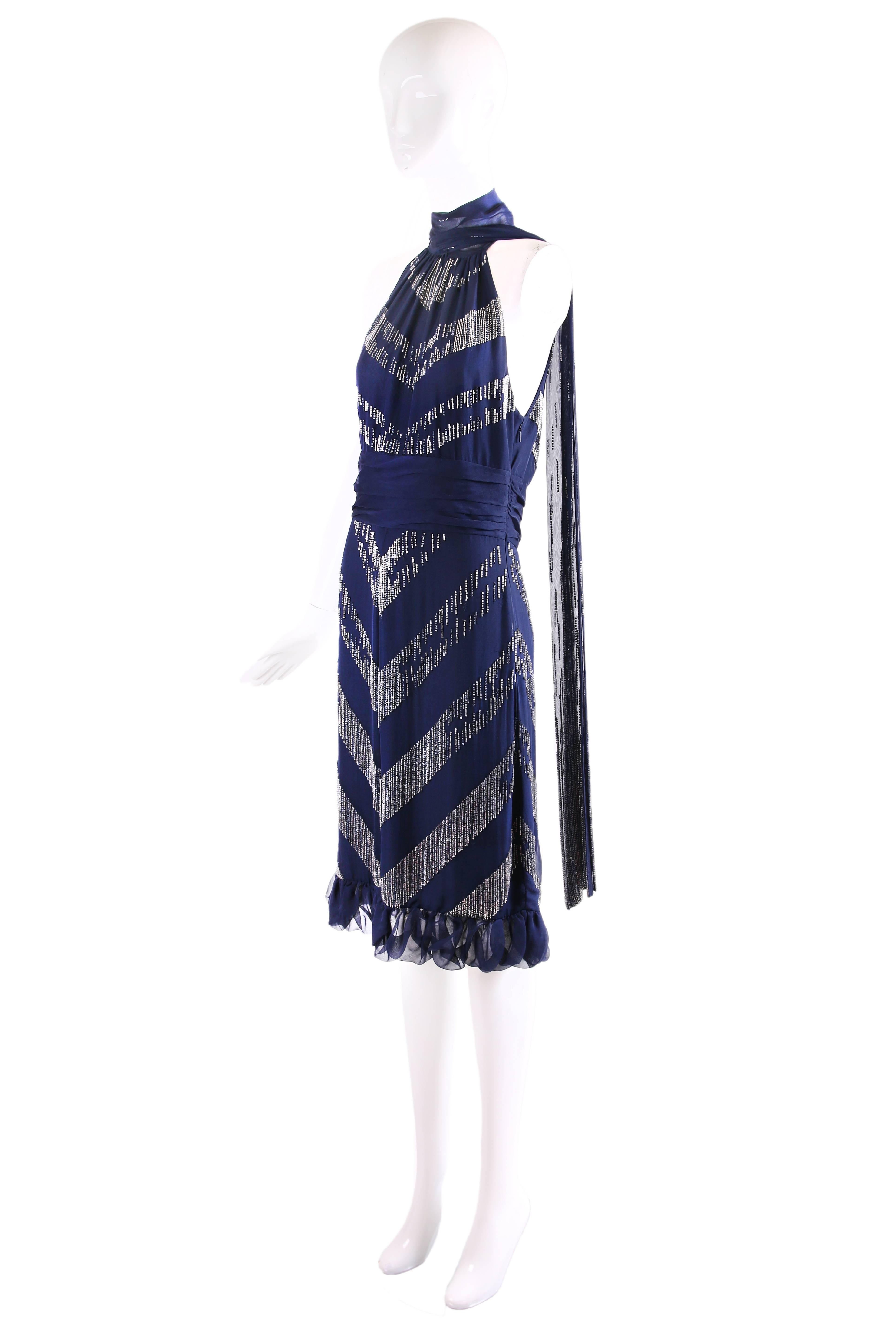 2006 Gucci navy blue silk halterneck cocktail dress featuring silver bugle beads in a chevron pattern. Dress features a plunging neckline, slit at center back, ruching at the waist, and oversized neckties which, when tied, hang dramatically down the