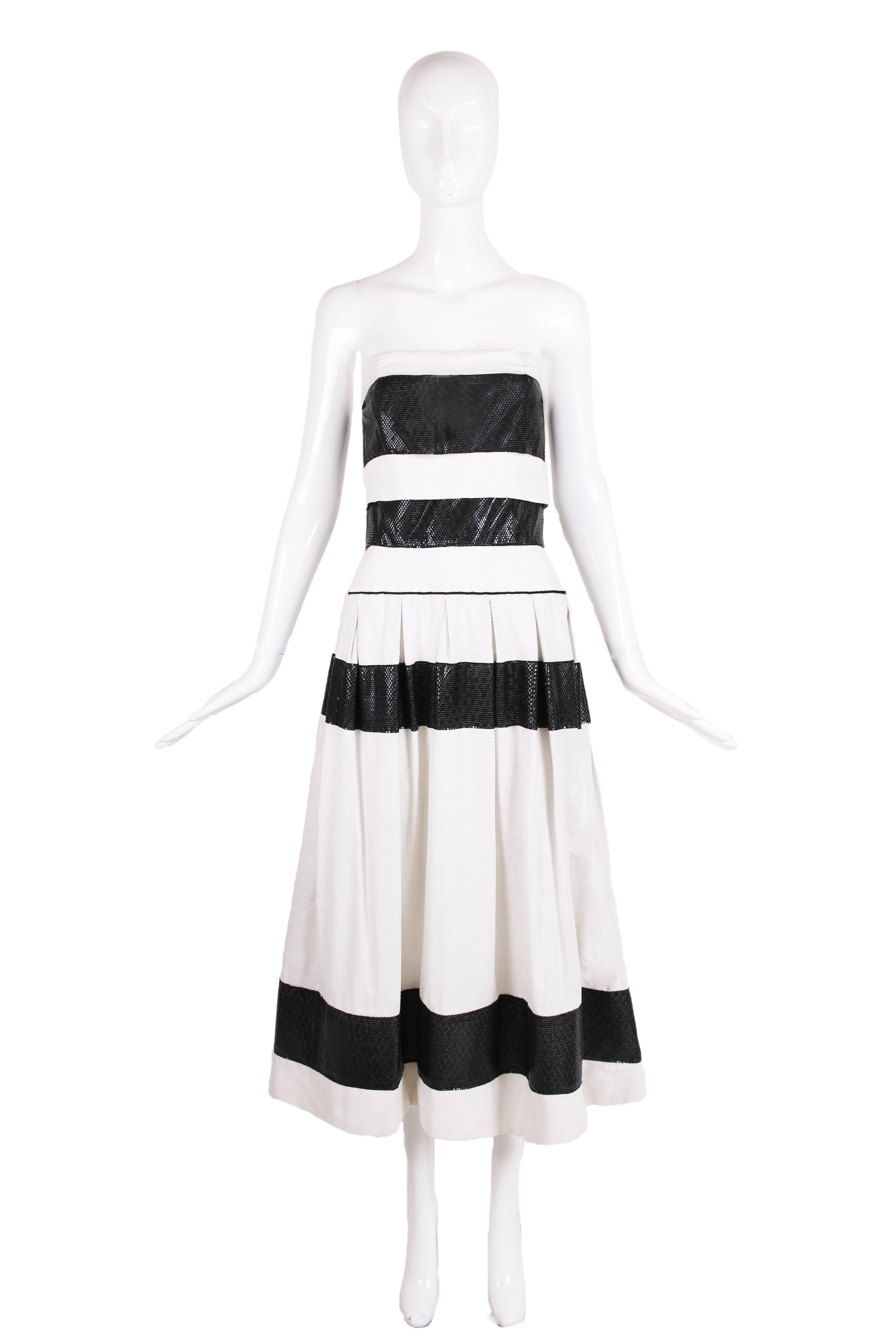 Vintage Chanel for Bergdorf Goodman white waffled cotton strapless cocktail dress with four contrasting black bands of a textured synthetic material. There is boning at the interior bodice, a nipped waist and full skirt with box pleats off a drop at