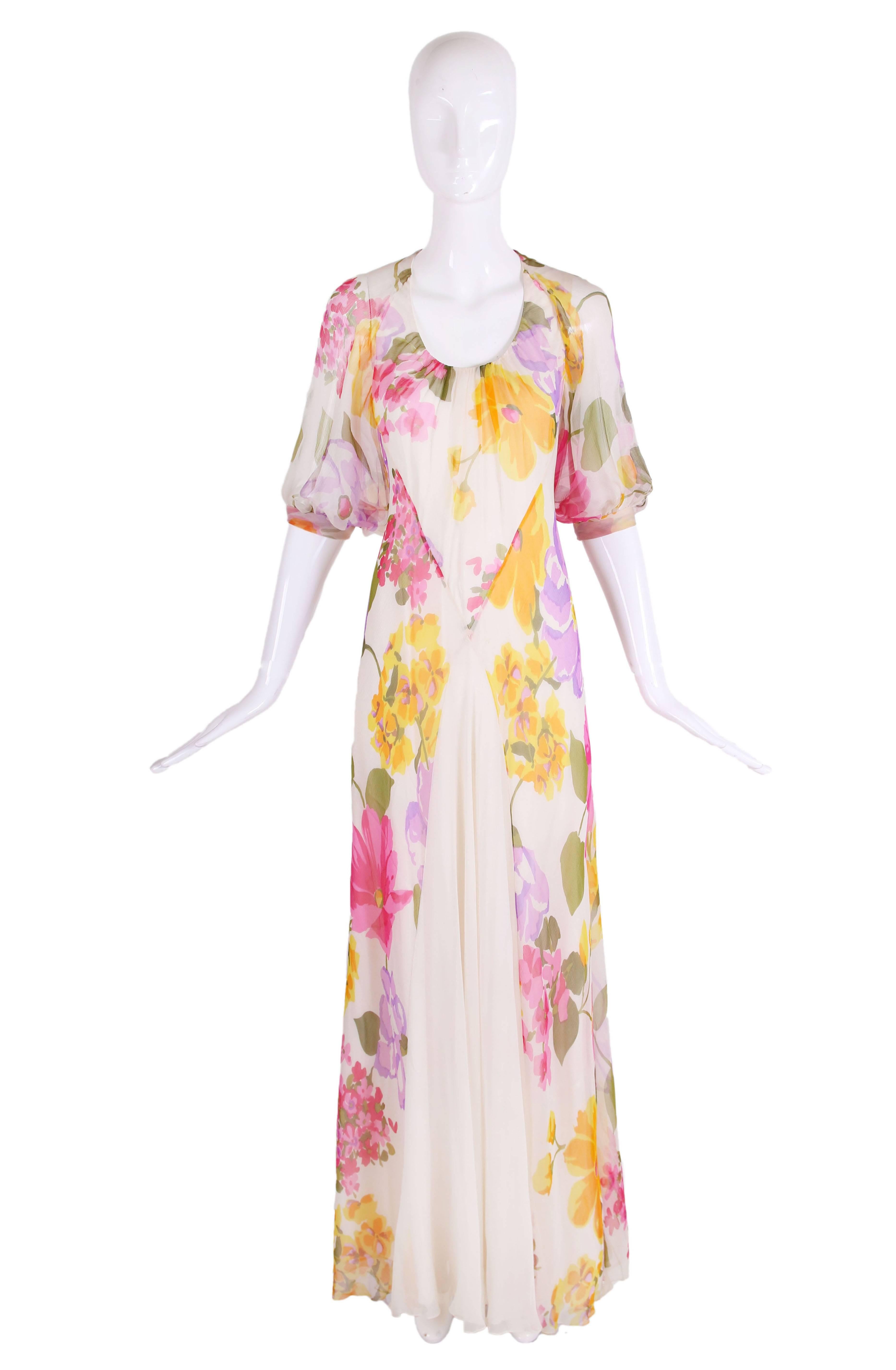 1970's Stavropoulos bias cut white silk chiffon evening gown with floral pattern in yellow, pink, purple, orange and green. Gown is made from a double layer of silk, has short sleeves with band and white panel at front. In excellent condition -