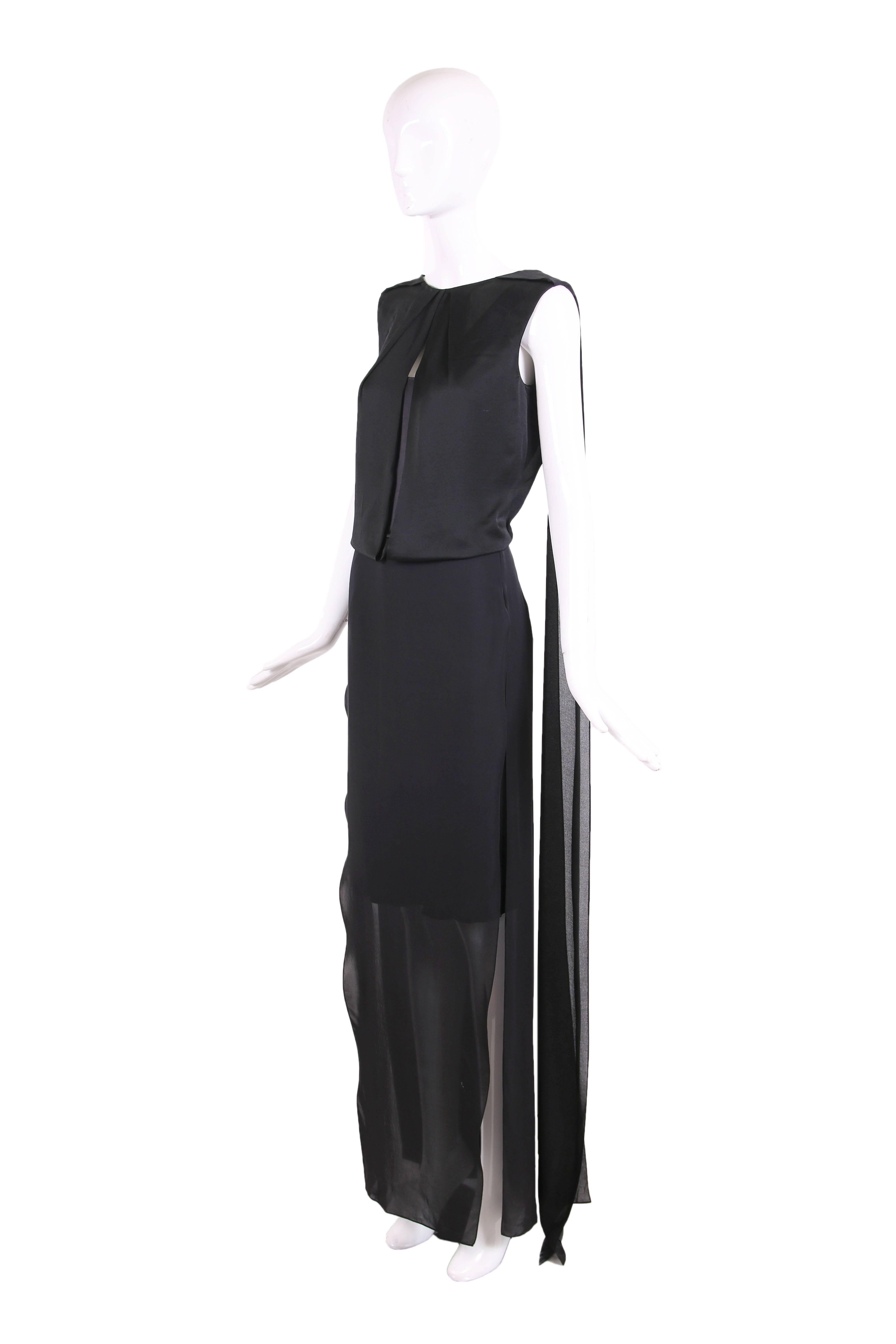 Tom Ford black silk gown which features a sheath overlay and scarf attachments at the back. At the interior is a black silk charmeuse mini dress with a deep scoop neckline at the front and deep V-neckline at the back. On top of that is a panel of