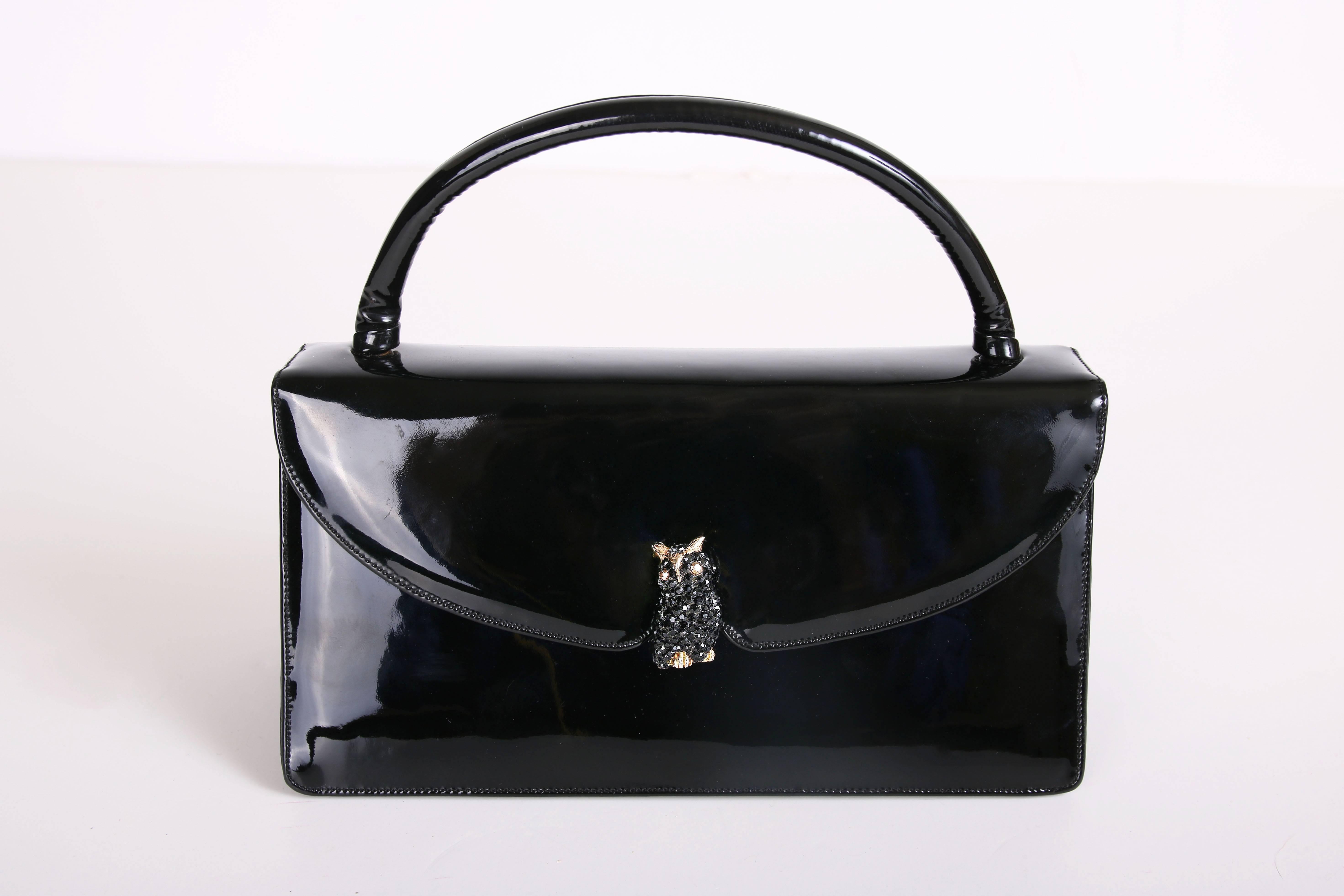 Vintage Judith Leiber black patent leather clutch handbag with gold-toned and black rhinestone owl detail at front closure. Interior has three separate compartments, one zipper pocket and one open pocket. Judith Leiber logo at interior. In excellent