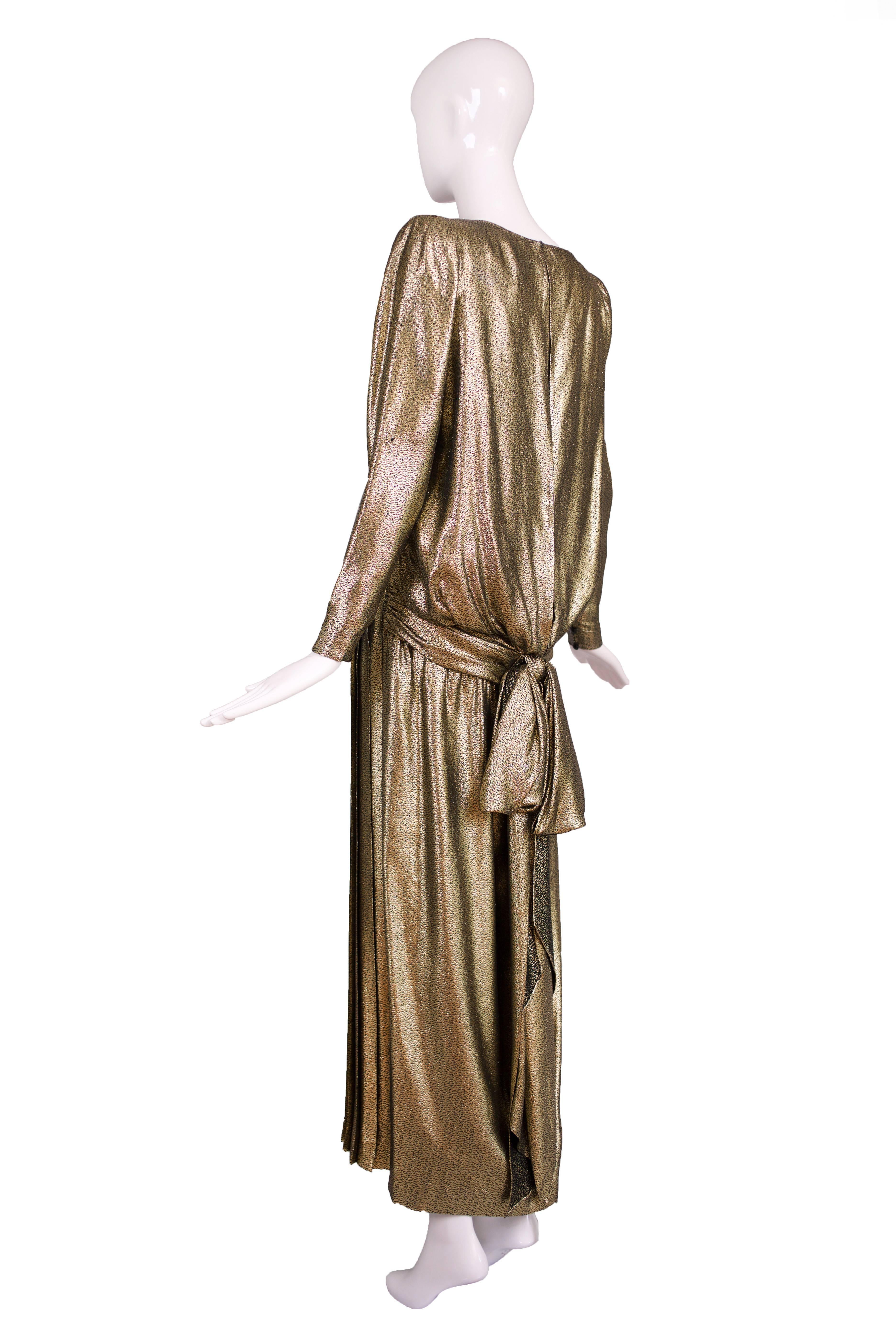 A 1980's Valentino Boutique label gold lame gown with a dropped waist, knife-pleated skirt and an oversized, draped bow at the back. Lined with organza. In very good to excellent condition with one tiny area of wear to the fabric of the left sleeve