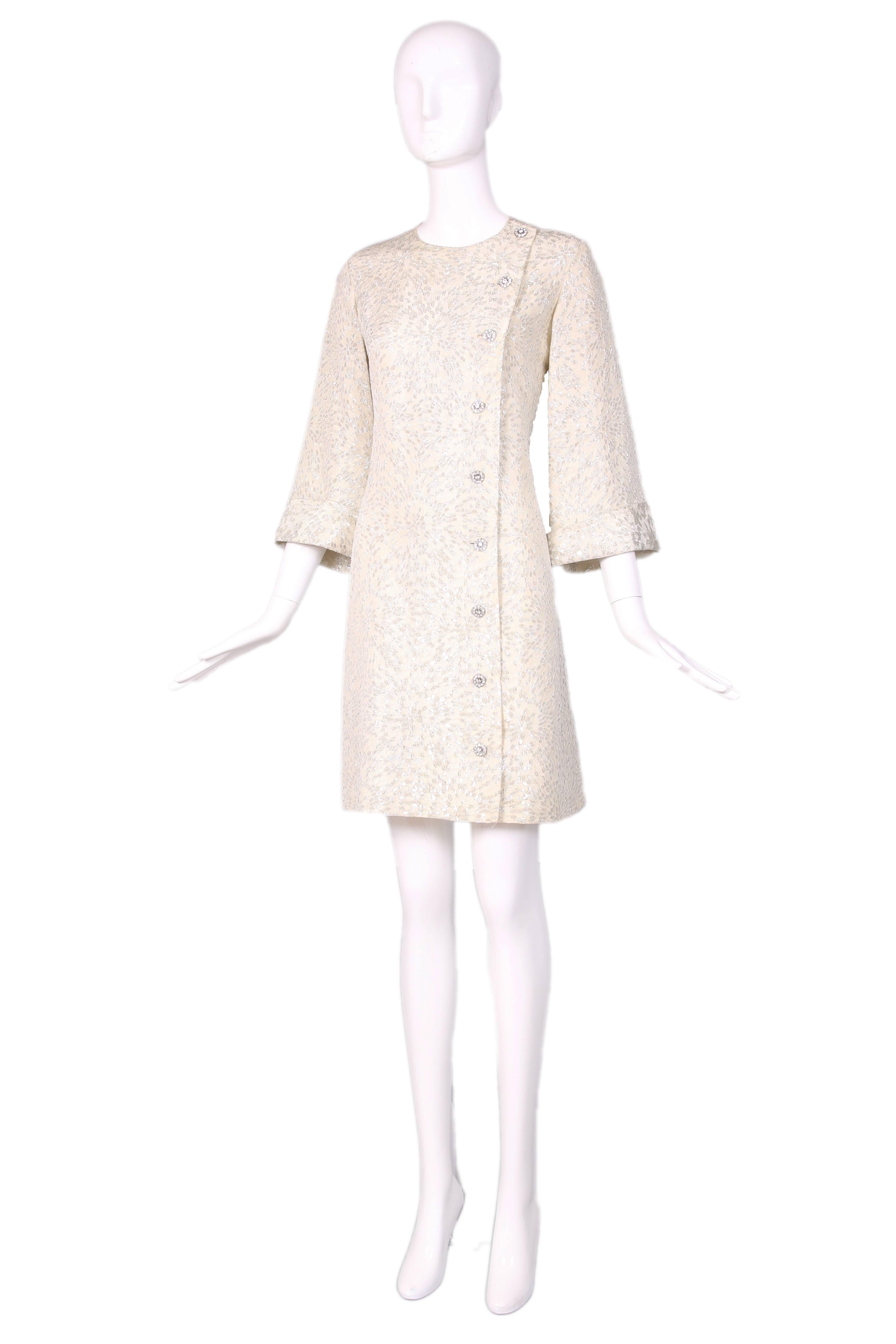 Circa 1968 Yves Saint Laurent silver lurex brocade coat dress with a slight swing silhouette, cuffed bell sleeves and rhinestone embellished buttons. Fully lined at the interior. Size tag 38. Please consult measurements. In excellent condition.
