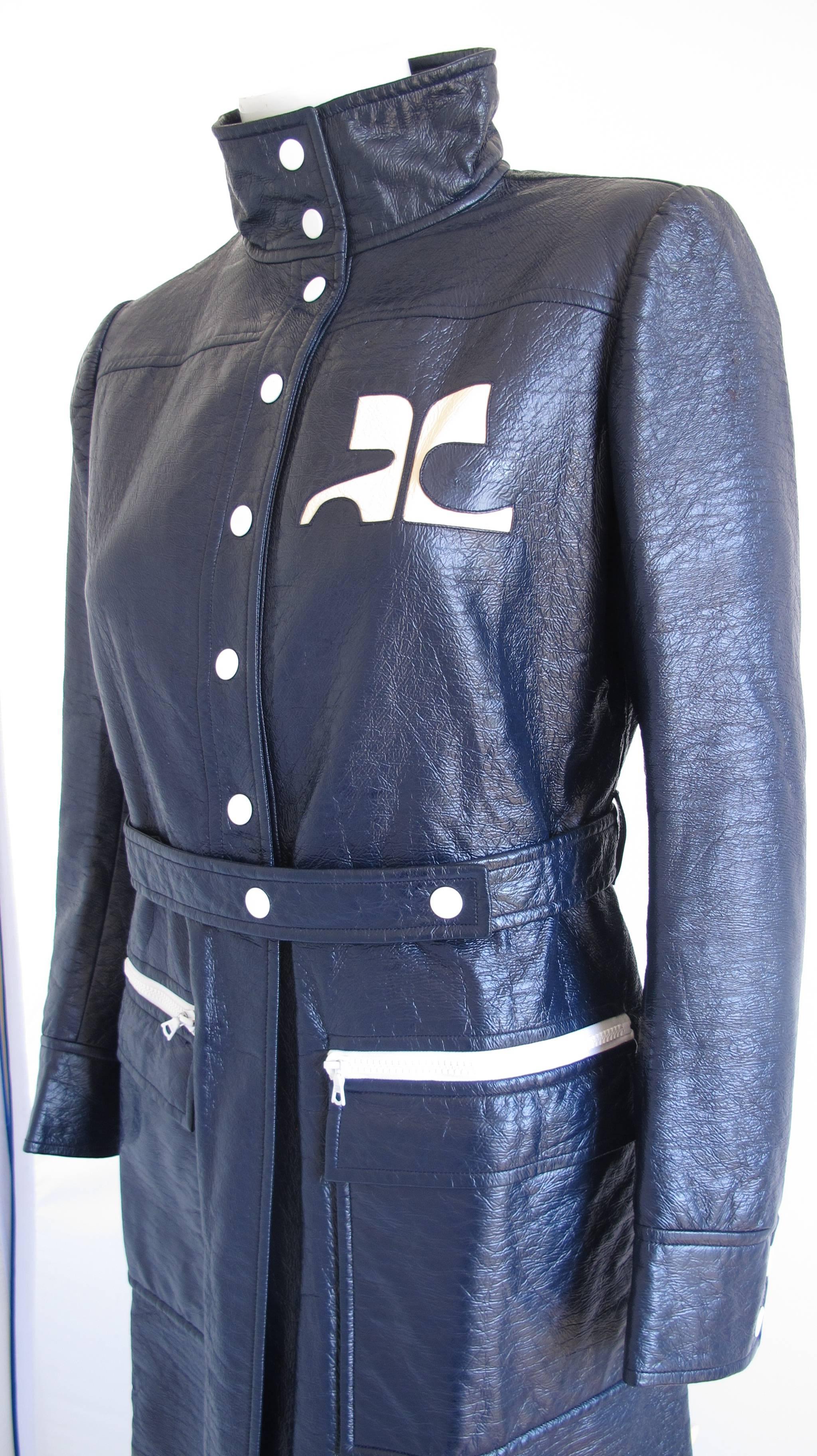 Iconic Courreges vinyl trench in navy blue with painted button snap front closure and oversize patch pockets with top zip closure. In excellent condition with faint almost imperceptible fading at the top back neck lining. Labeled Courreges size C.