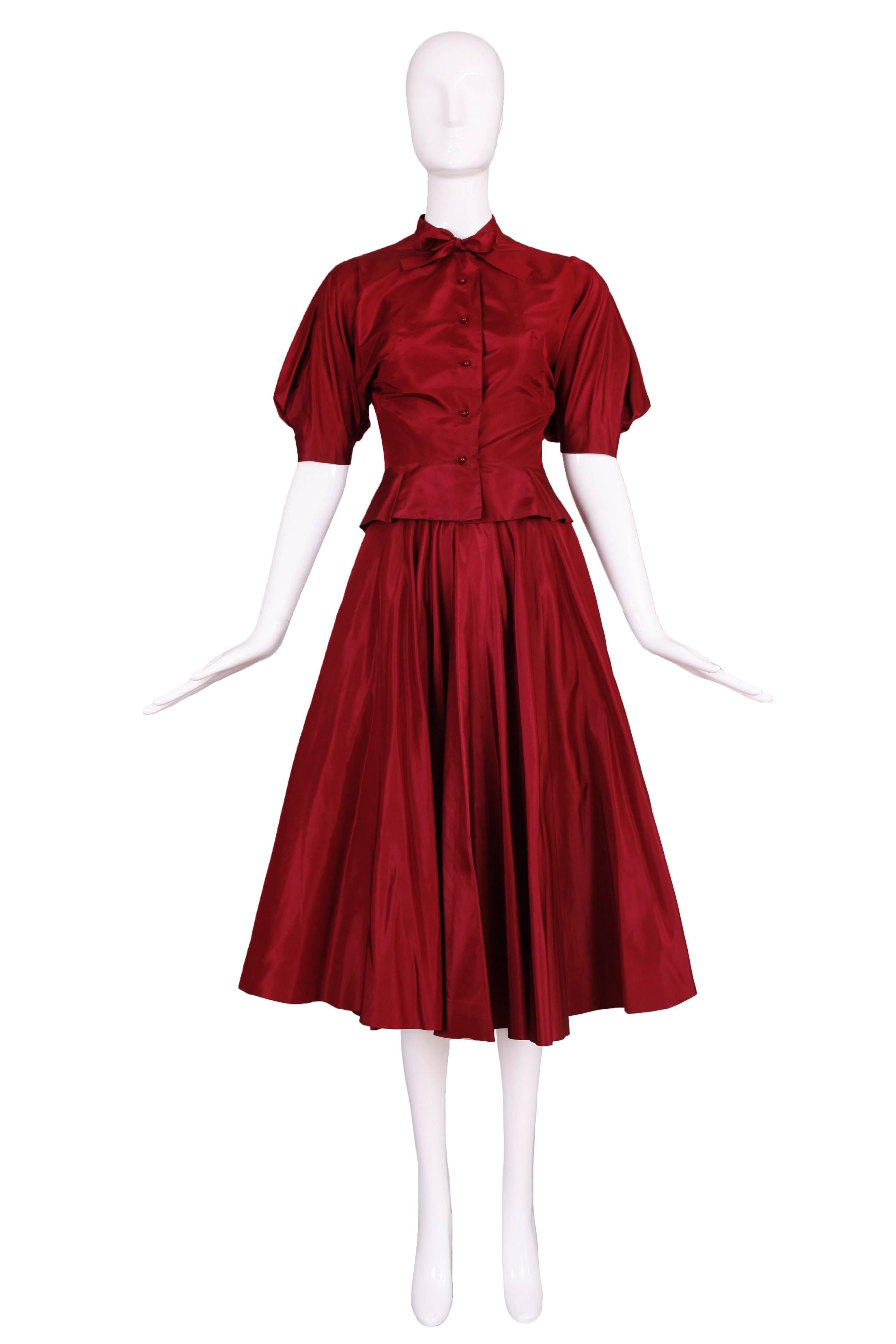 A 1981 Madame Gres haute couture dark scarlet silk taffeta skirt and blouse ensemble with matching high-heeled shoes size 6 1/2. Features the iconic Mme Gres gathered/balloon sleeve, shiny round button closures down center front, neck ties and a