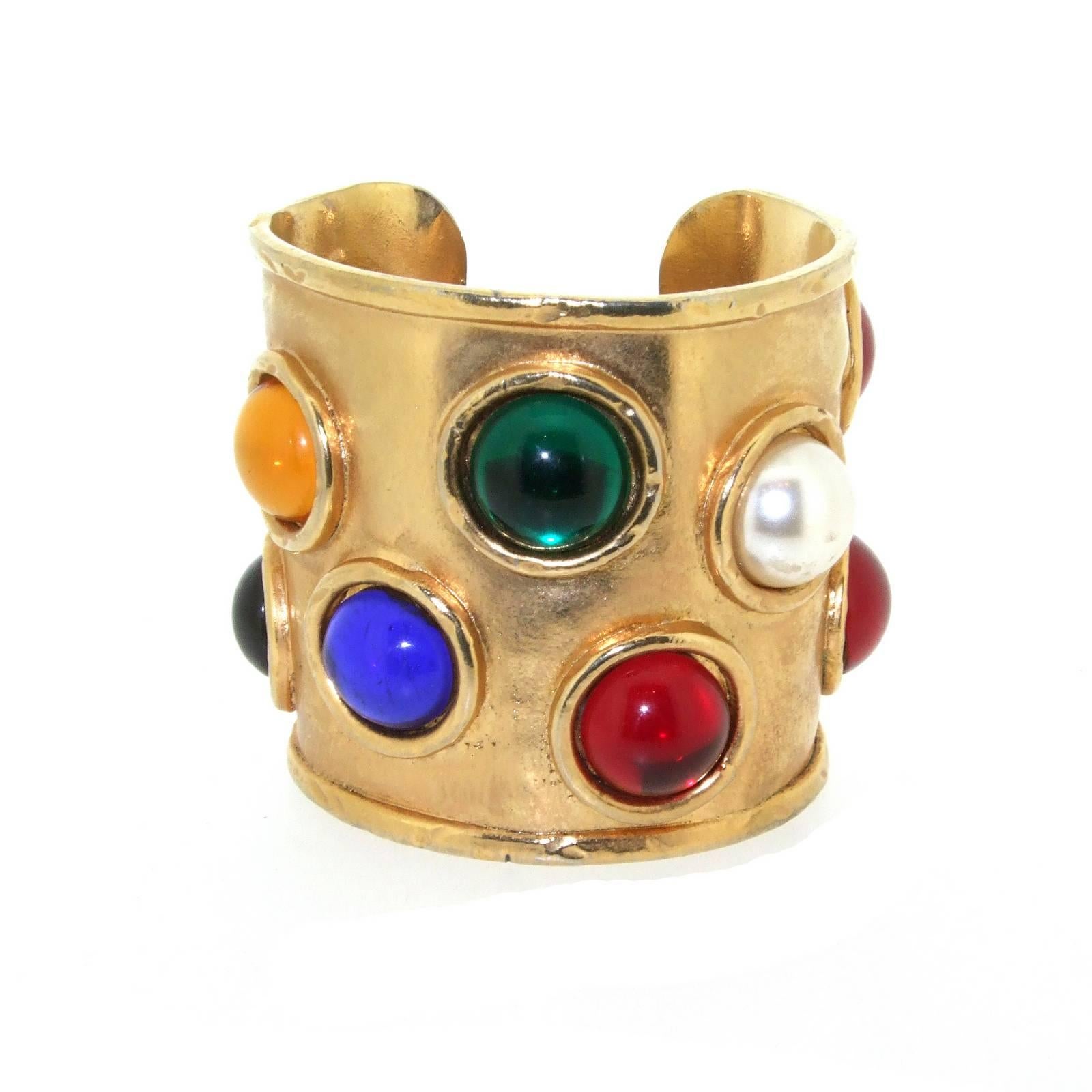 A vintage cuff bracelet by Edouard Rambaud Paris. Made from gold plated brass, time worn and set with glass multi-coloured and pearl glass stones. 

It measures 6cm high by 6.1cm wide, 7 inches around the wrist. The dark shadow in the photo is