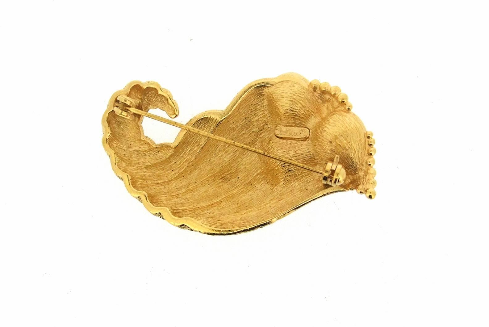 A vintage Christian Dior brooch featuring red crystal hearts in a gold shell. 
In gold plated costume metal.

It measures 4.8cm high by 3cm at the widest point.